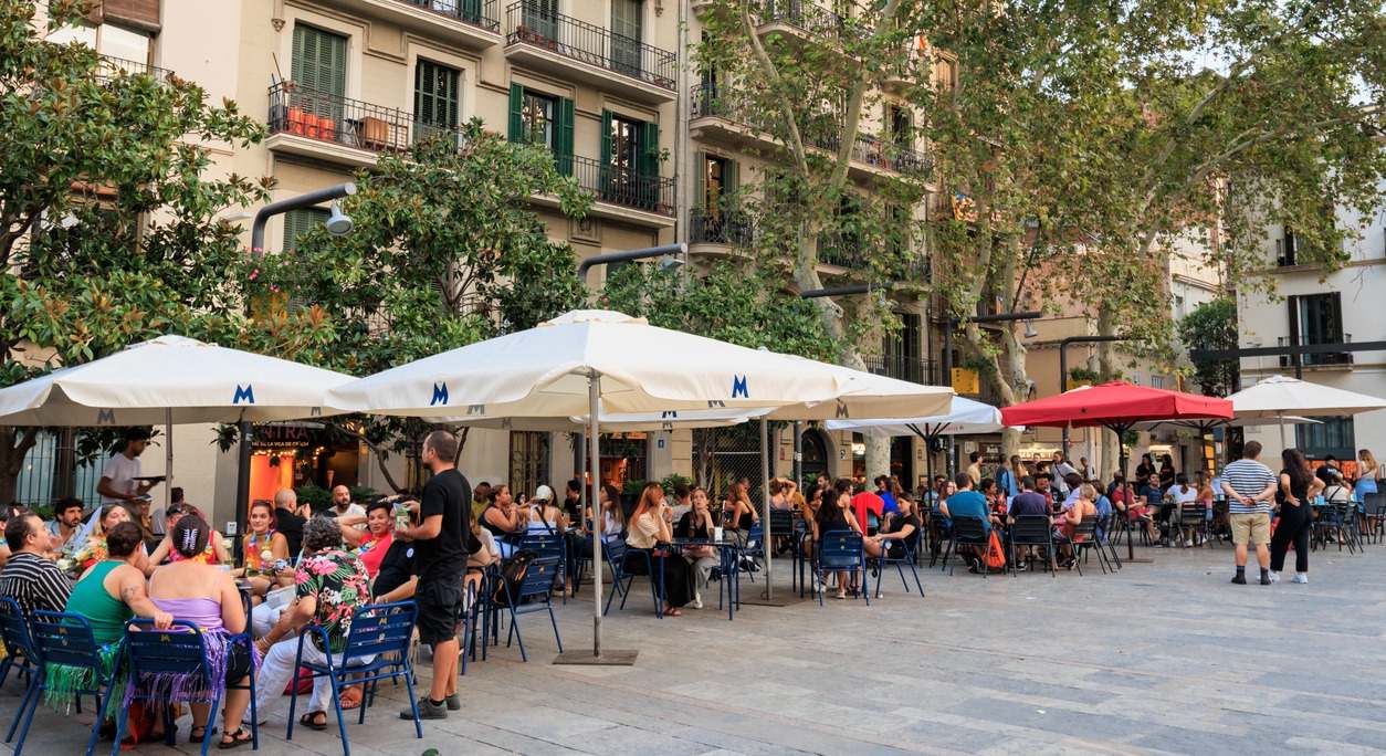 Terrazas de un bar con mucha gente y sombrillas