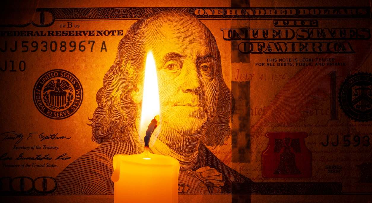 Dólar en la oscuridad detrás de una vela