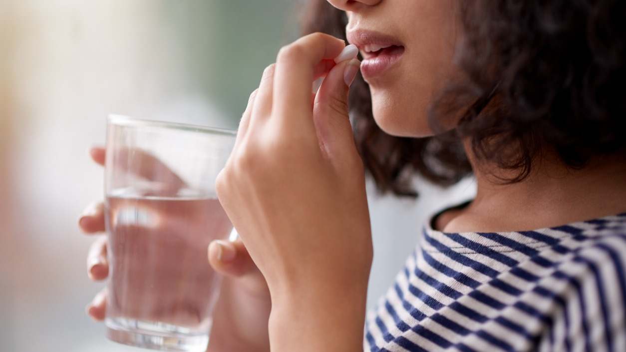mujer toma pastilla con agua