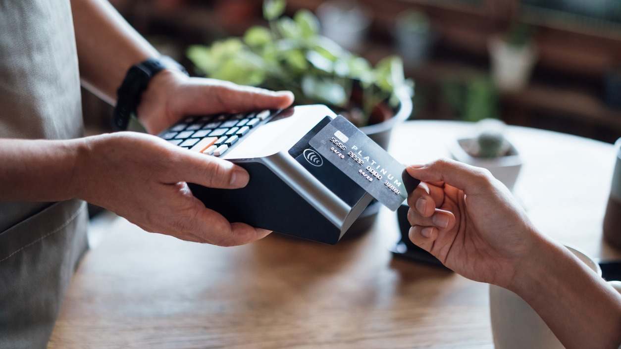 Persona acercando una tarjeta de crédito a un datáfono
