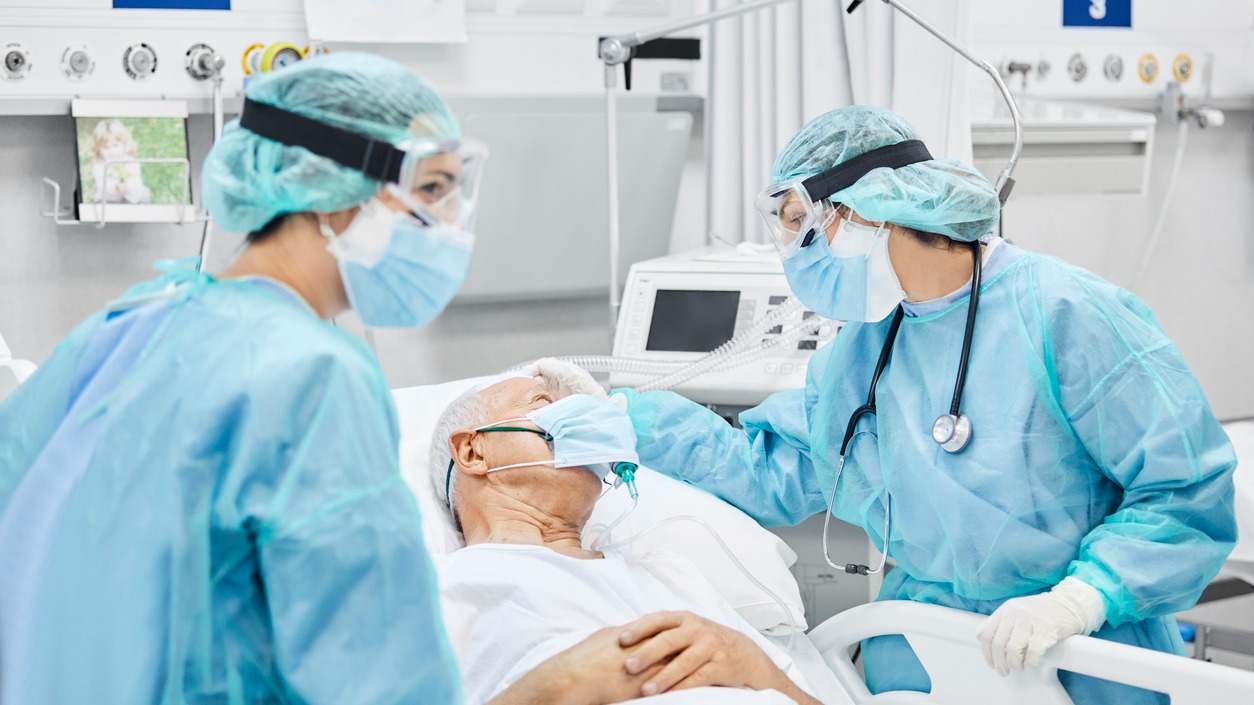 Médicos con mascarilla tratando a un enfermo, también con mascarilla