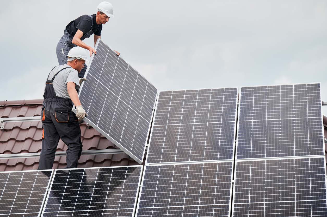 Hombre trabajador montando paneles solares en el techo de la casa