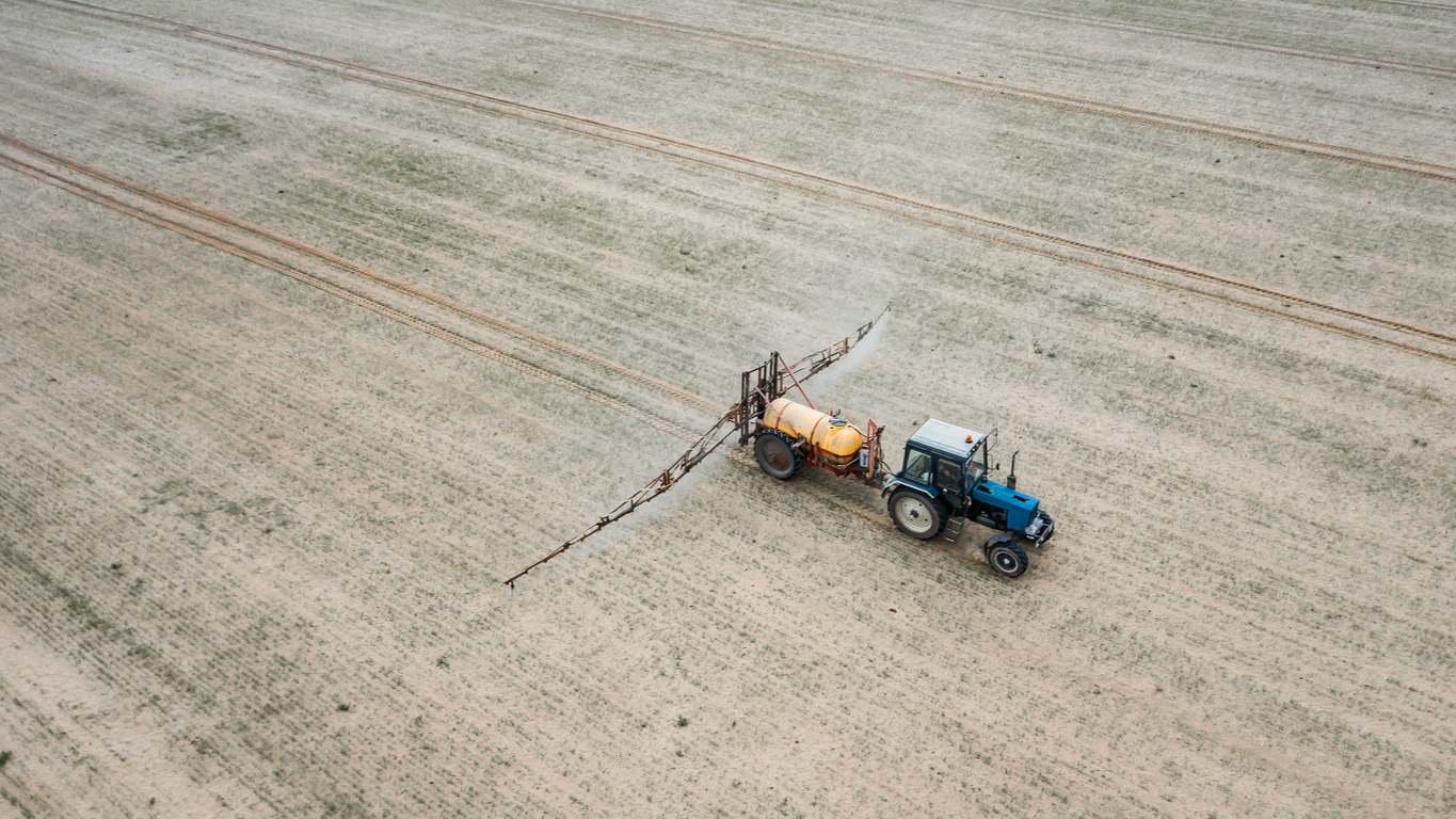 Tractor trata el campo con pesticidas vista superior