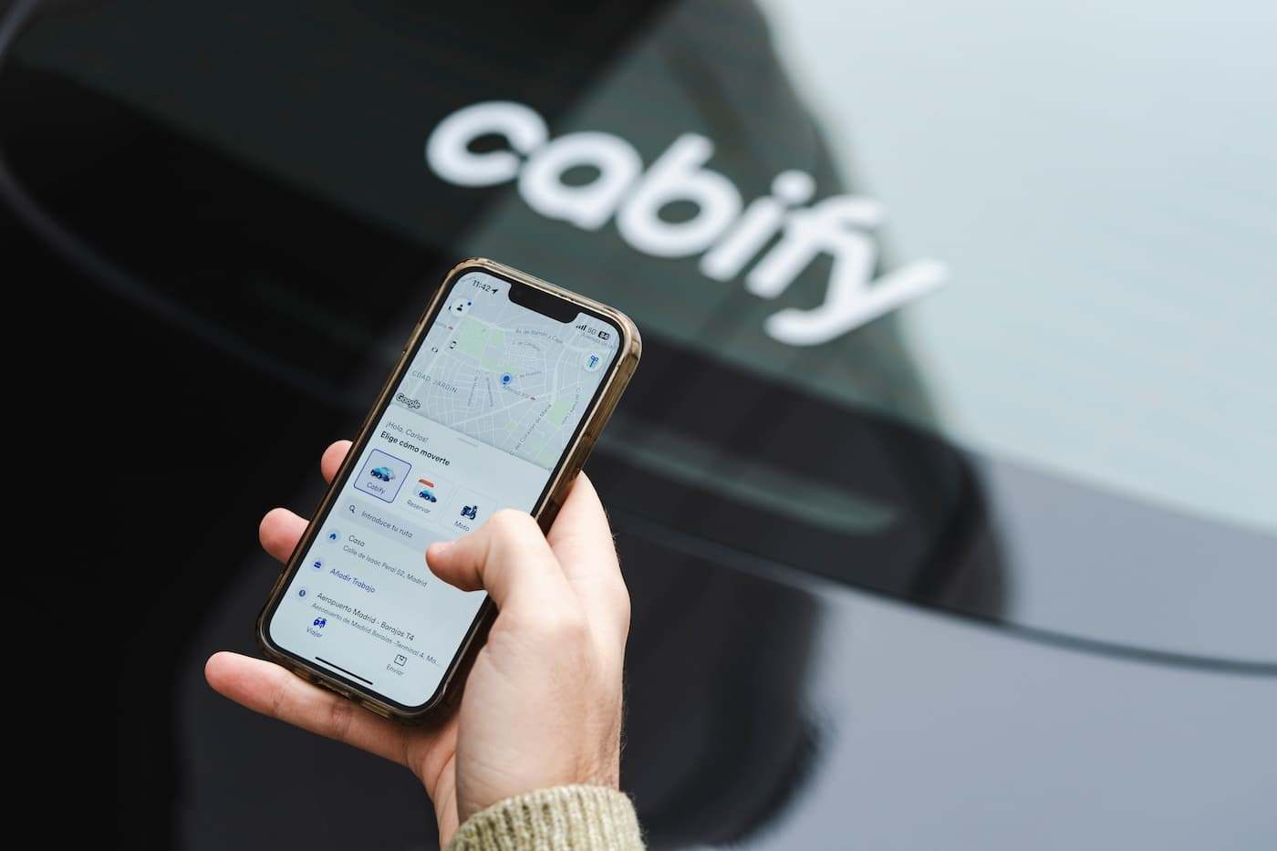 App de Cabify junto a uno de sus vehículos. / Cabify