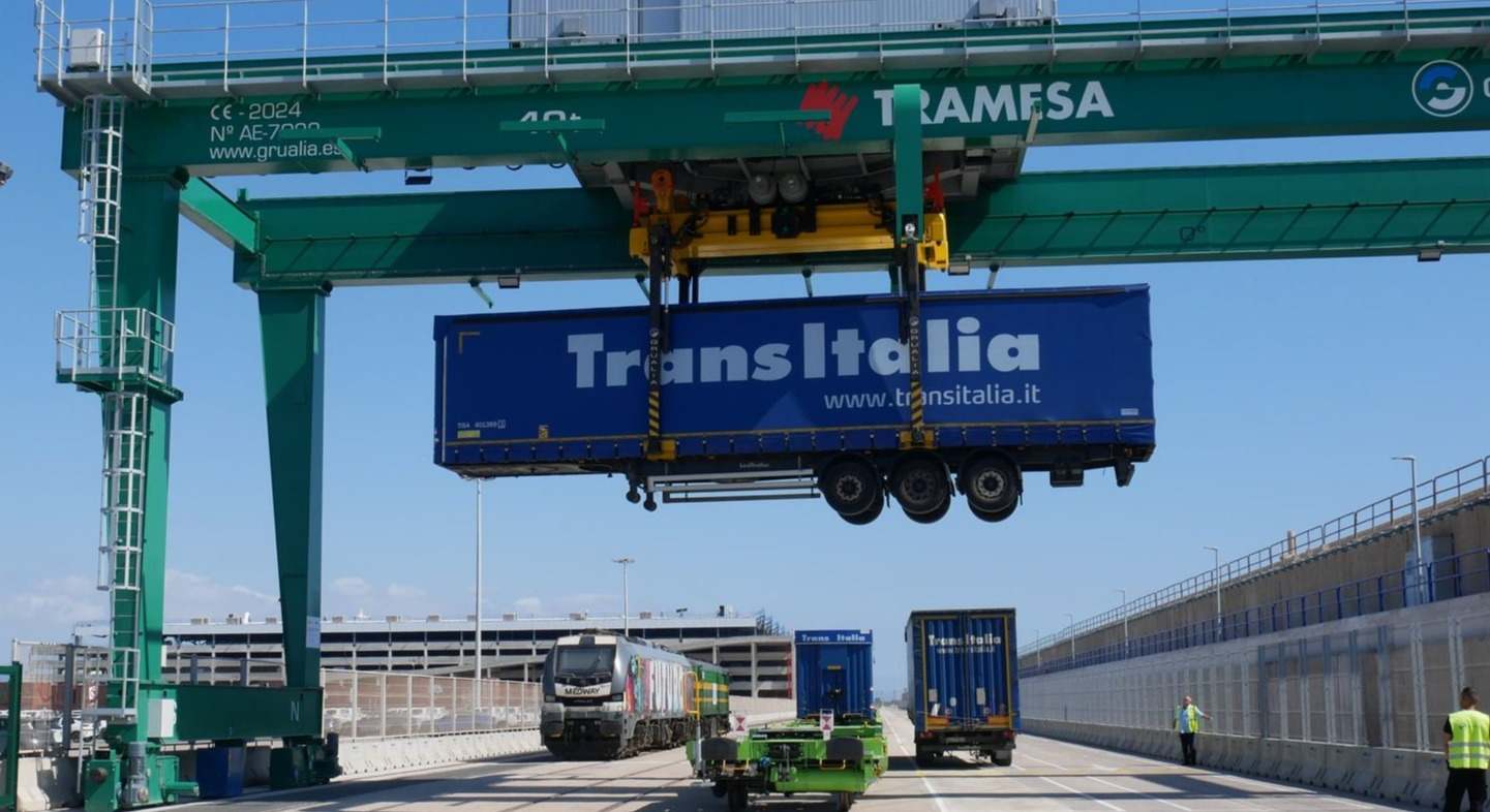 Una grúa sube un semirremolque a un vagón en el puerto de Valencia.