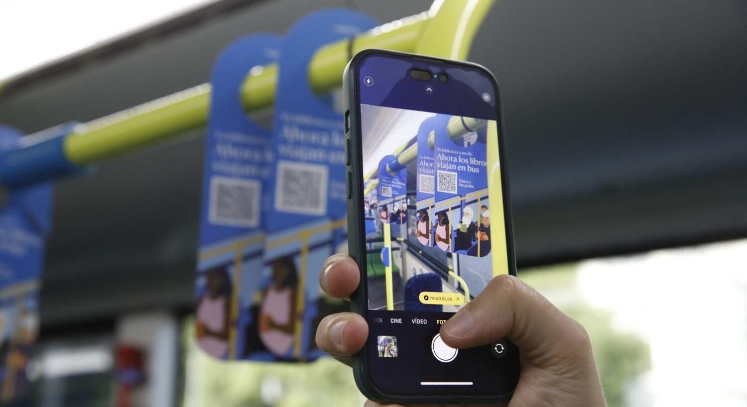 Una persona escanea con su móvil uno de los códigos QR de la campaña Tu biblioteca a un clic del Ayuntamiento de Madrid