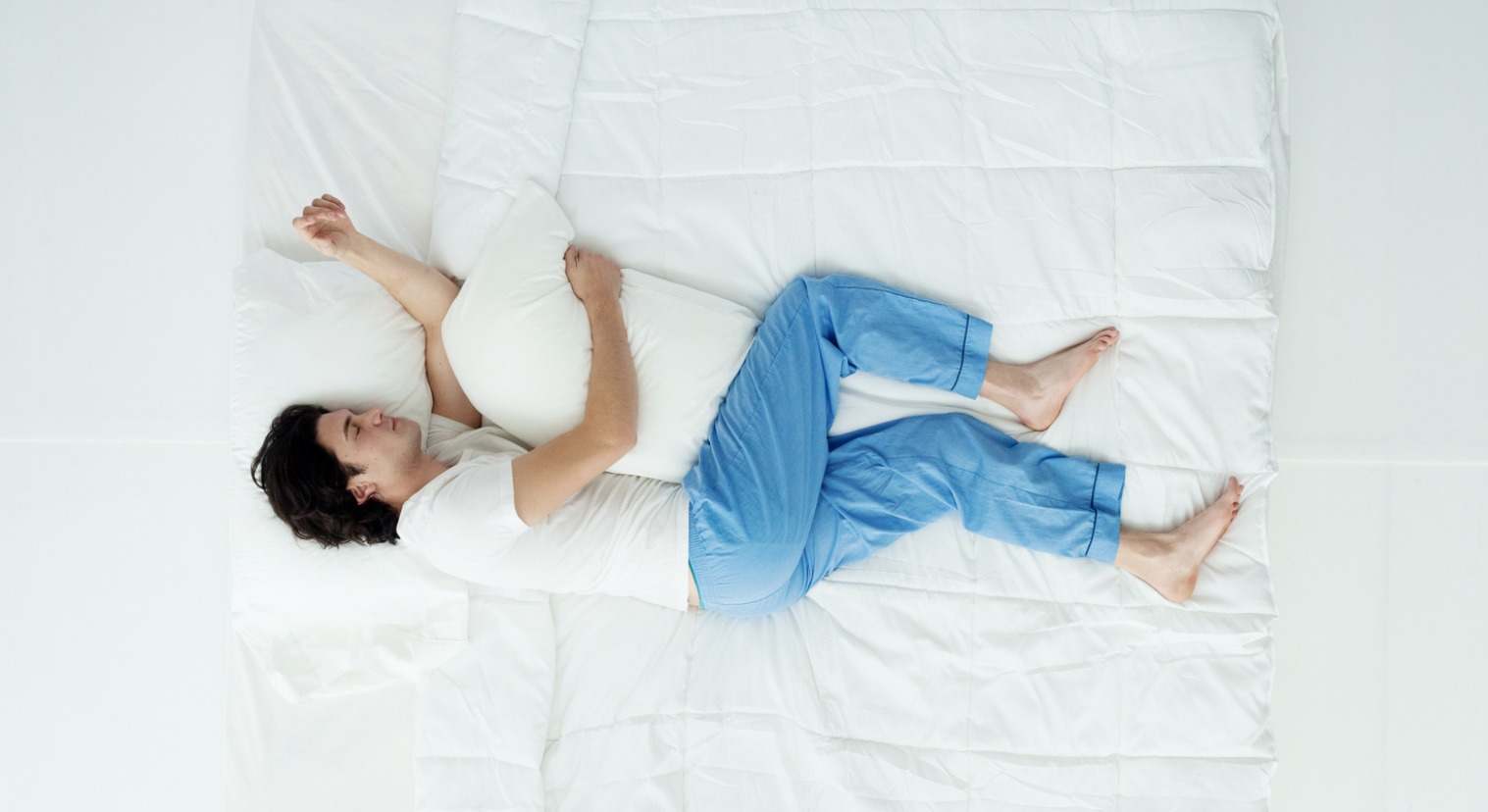 Hombre durmiendo en la cama abrazando una almohada