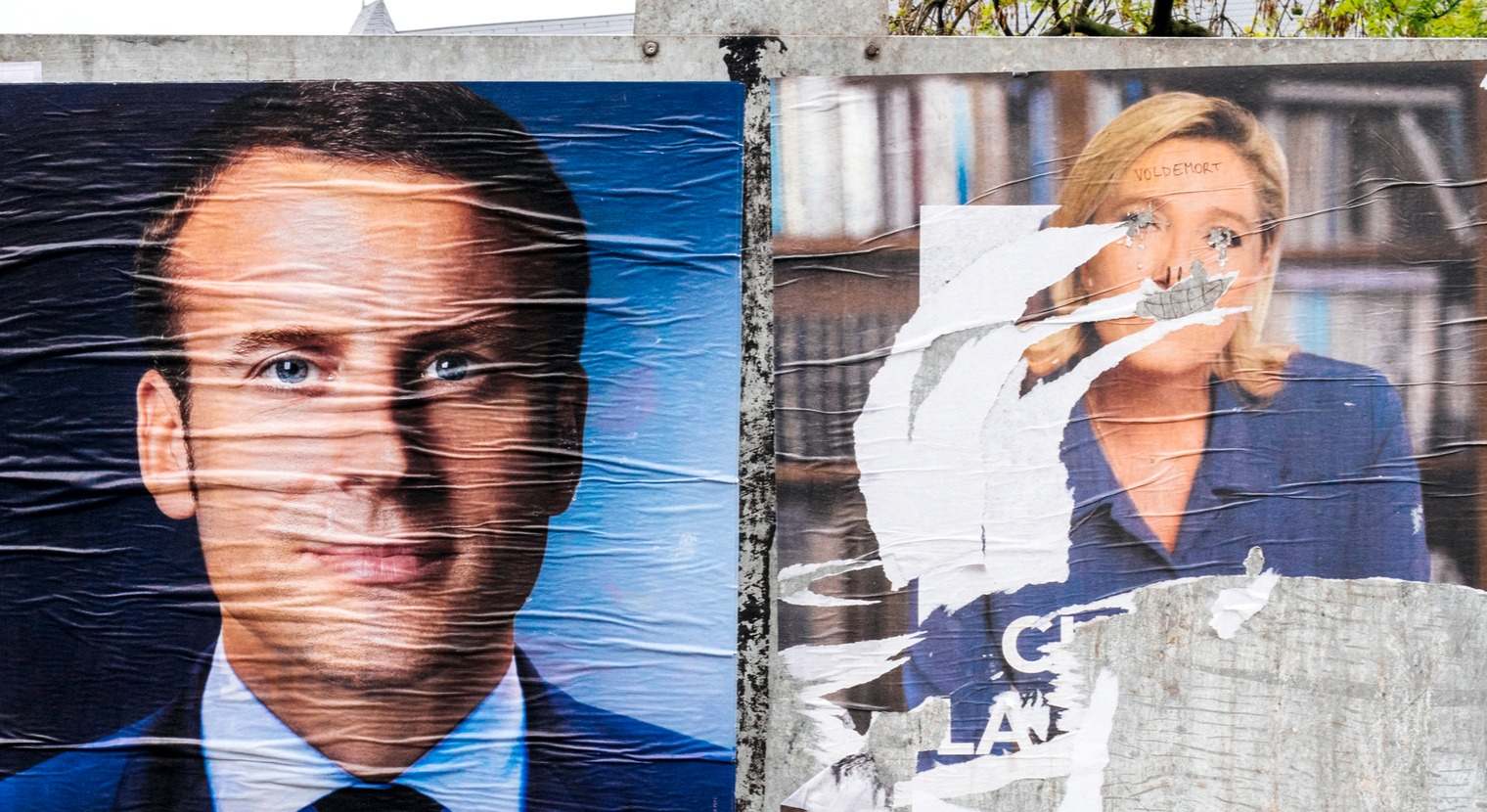 Dos carteles electorales deteriorados de Emmanuel Macron y Marine Le Pen