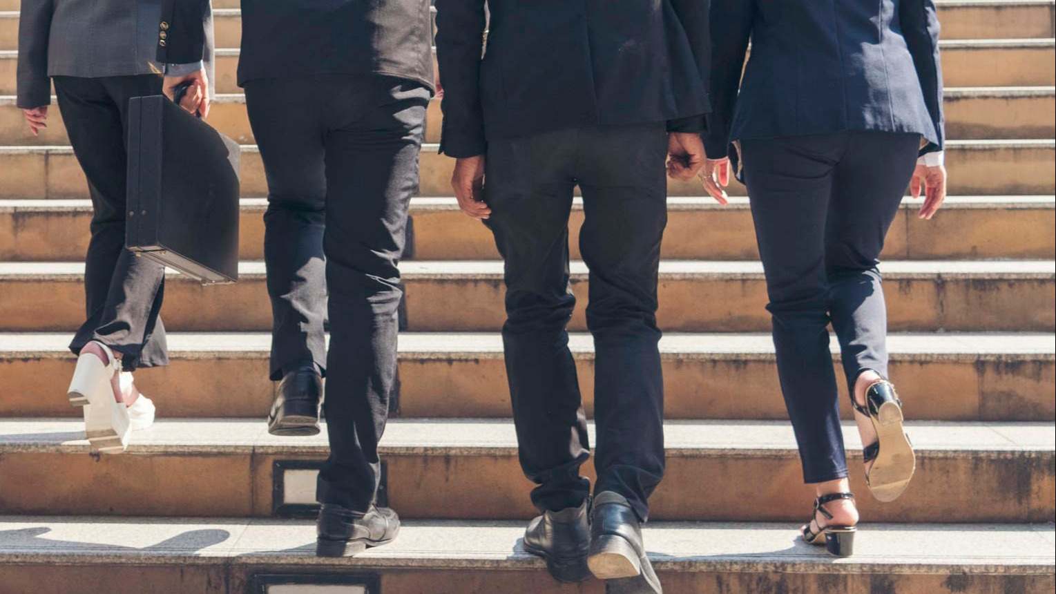 Mujeres y hombres trabajadores de oficina subiendo unas escaleras. Foto: iStock