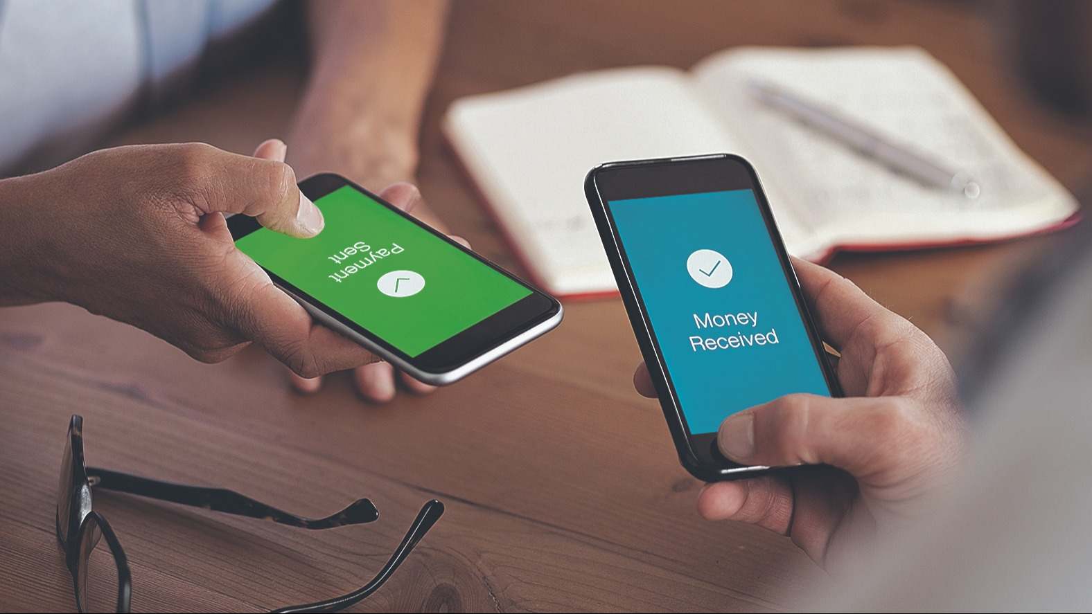 Dos móviles en la mano enviando y recibiendo dinero de forma online