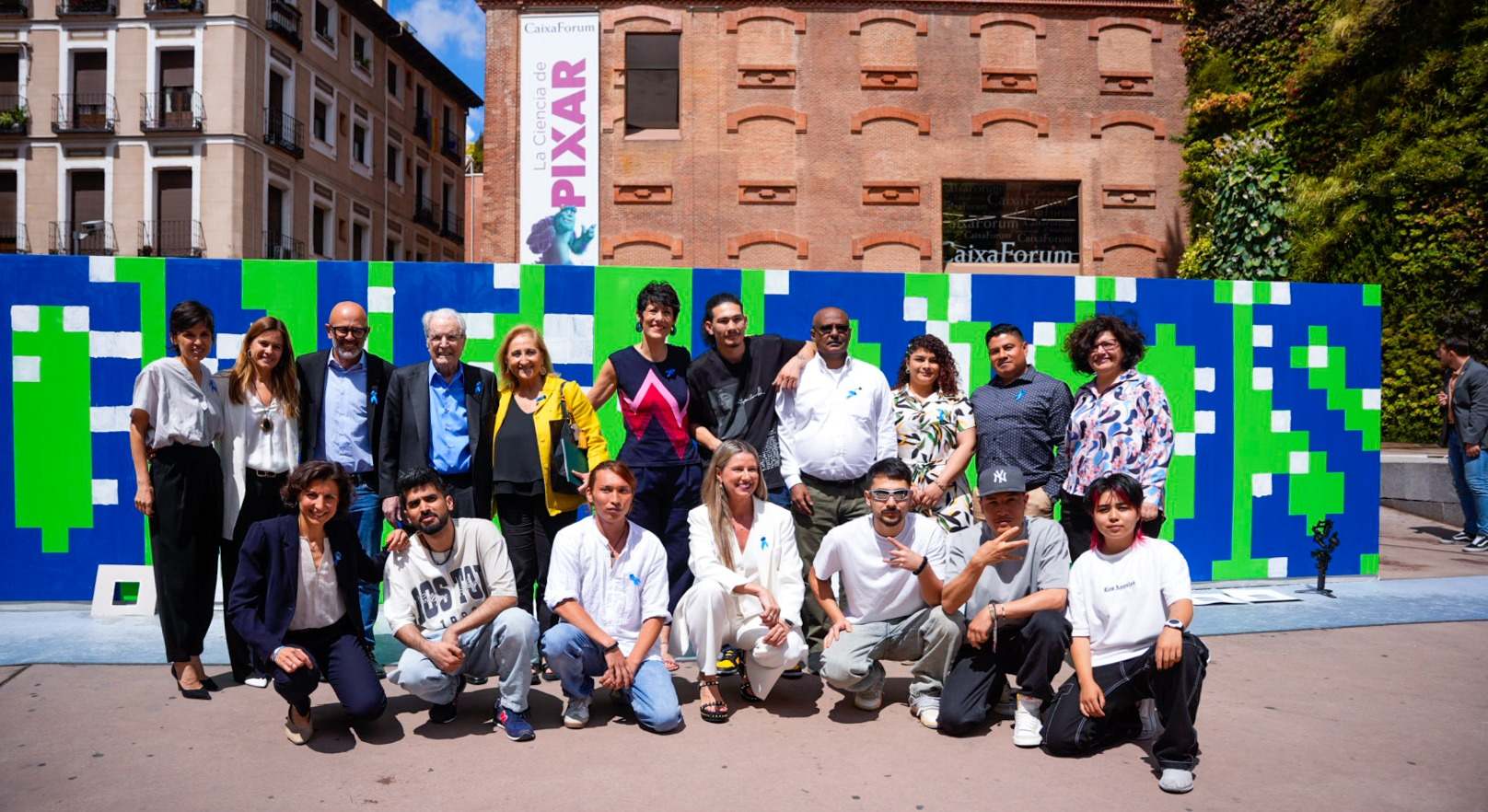 Los asistentes al acto del Día Mundial del Refugiado, frente al mural interactivo de Boa Mistura en CaixaForum Madrid