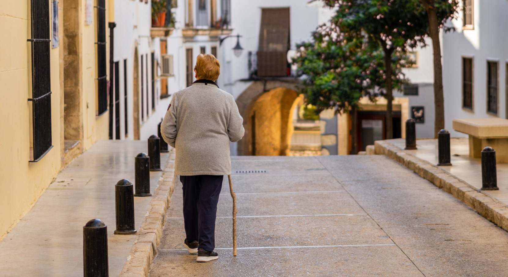 Mujer mayor caminado por la calle de espaldas