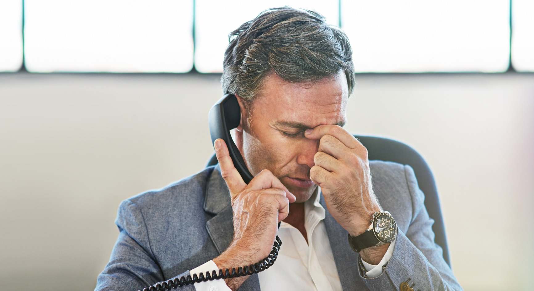 Empresario con cara de agotamiento sentado en su despacho