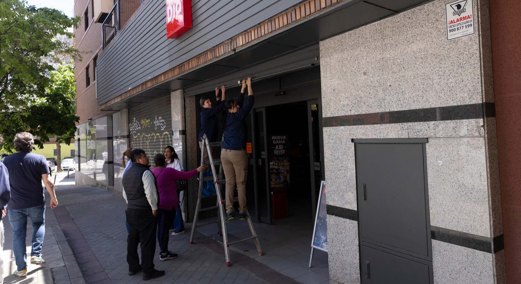 Dos empleadas de Dia abren a mano la persiana de un supermercado el pasado 28 de abril.
