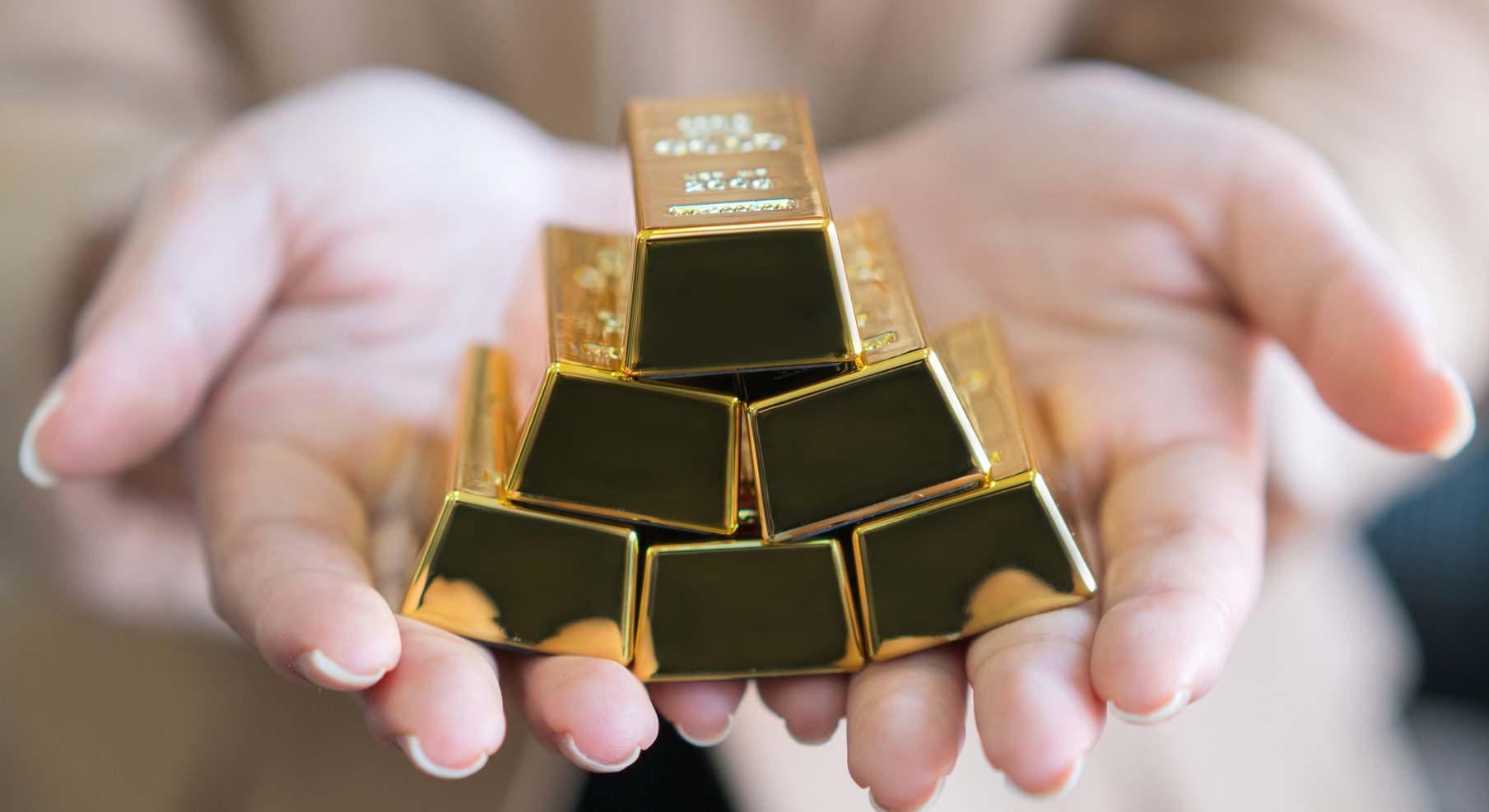 Una mujer sosteniendo unos lingotes de oro