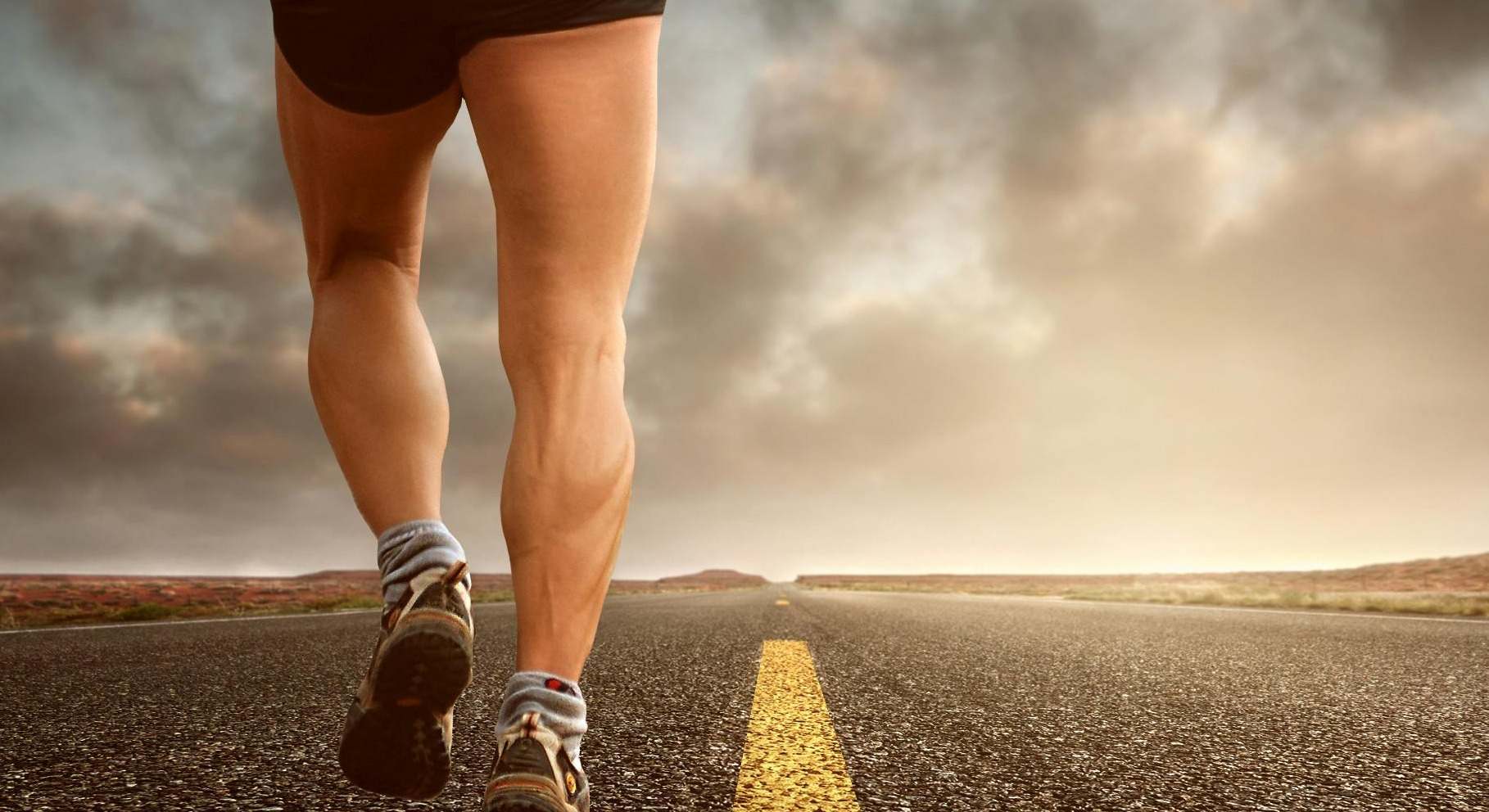 Un hombre con las piernas muy fuertes corre por una carretera