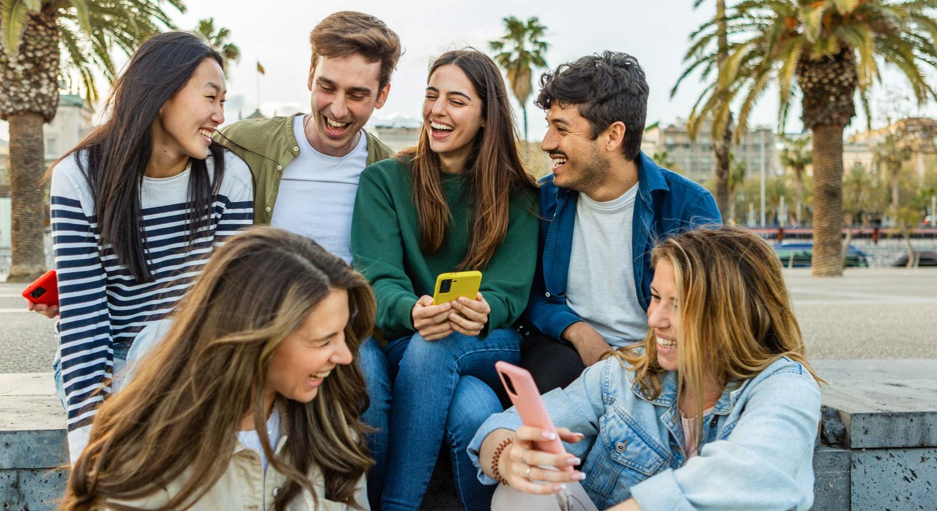 Grupo de jóvenes riendo con sus teléfonos móviles