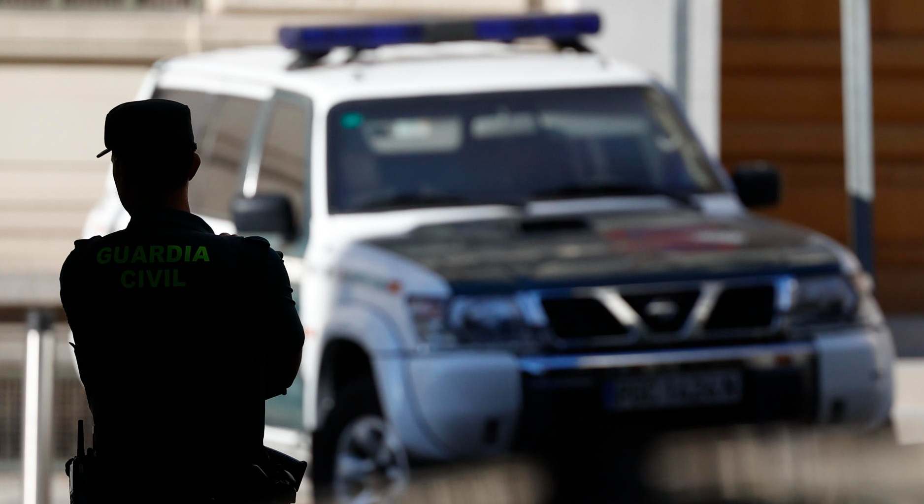 Coche de la Guardia Civil y agente de espaldas a contraluz