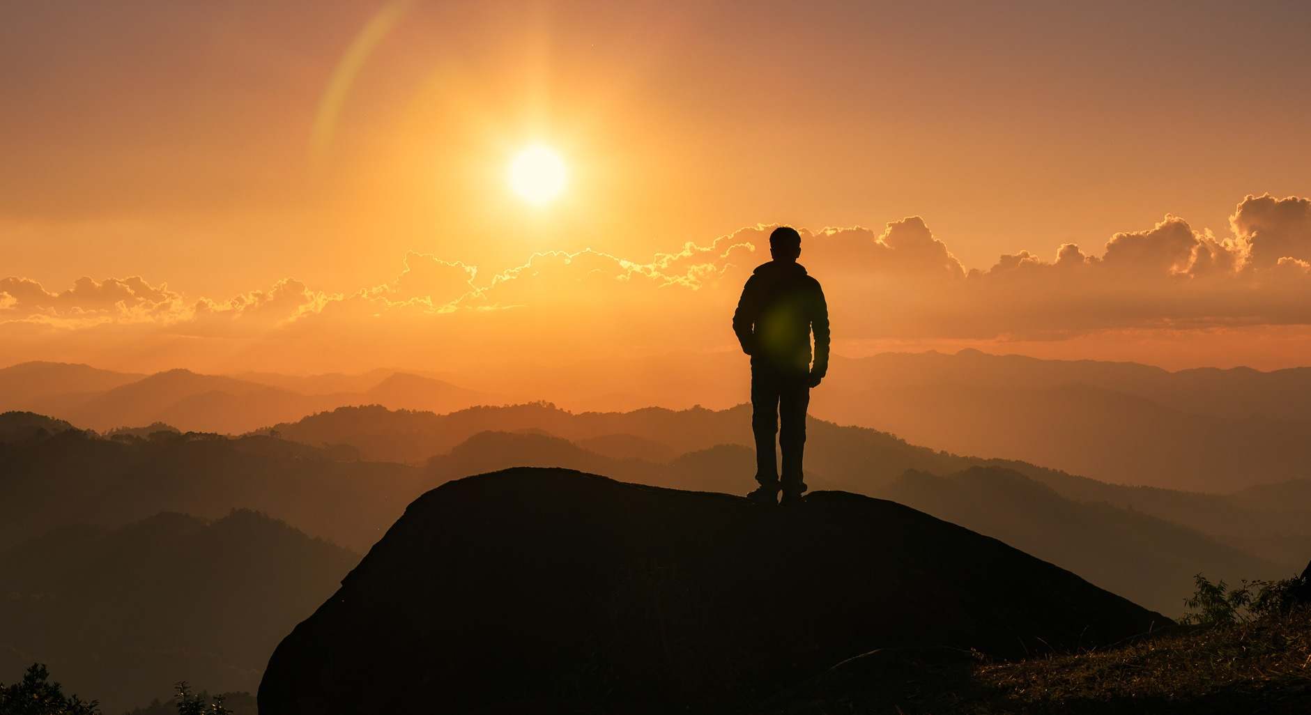 Silueta de un excursionista en la cima de una montaña en una puesta de sol