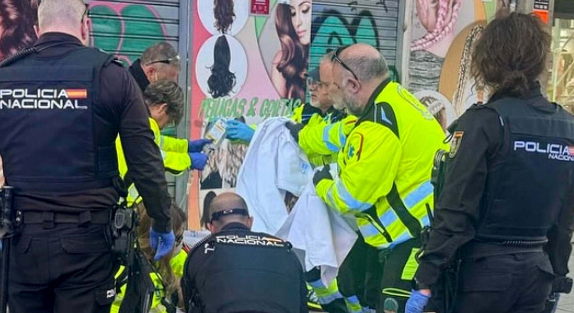 Varios sanitarios y Policía Nacional atendiendo al herido en Puente de Vallecas