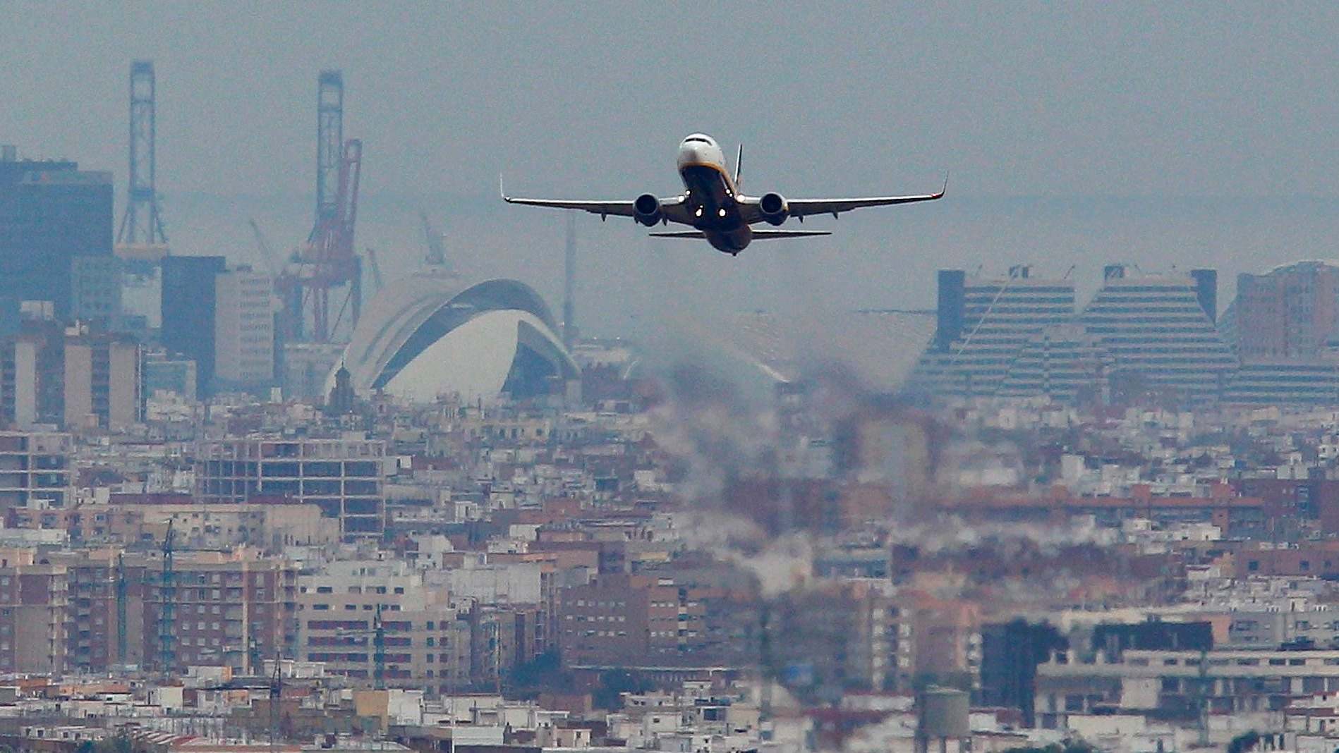 Un avión con la ciudad de Valencia al fondo.