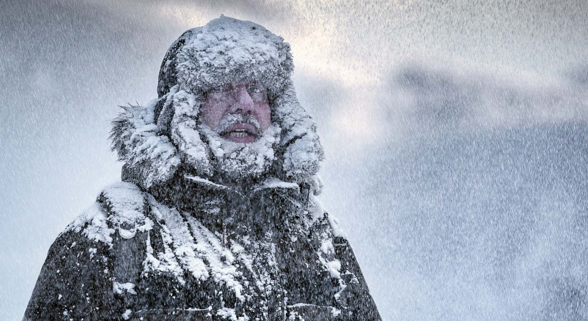 Un hombre con barba en mitad de una tormenta de nieve