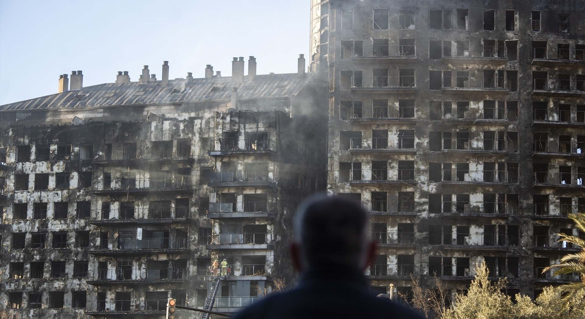 Un hombre observa la estructura del edificio tras el incendio en el barrio de Campanar, Valencia