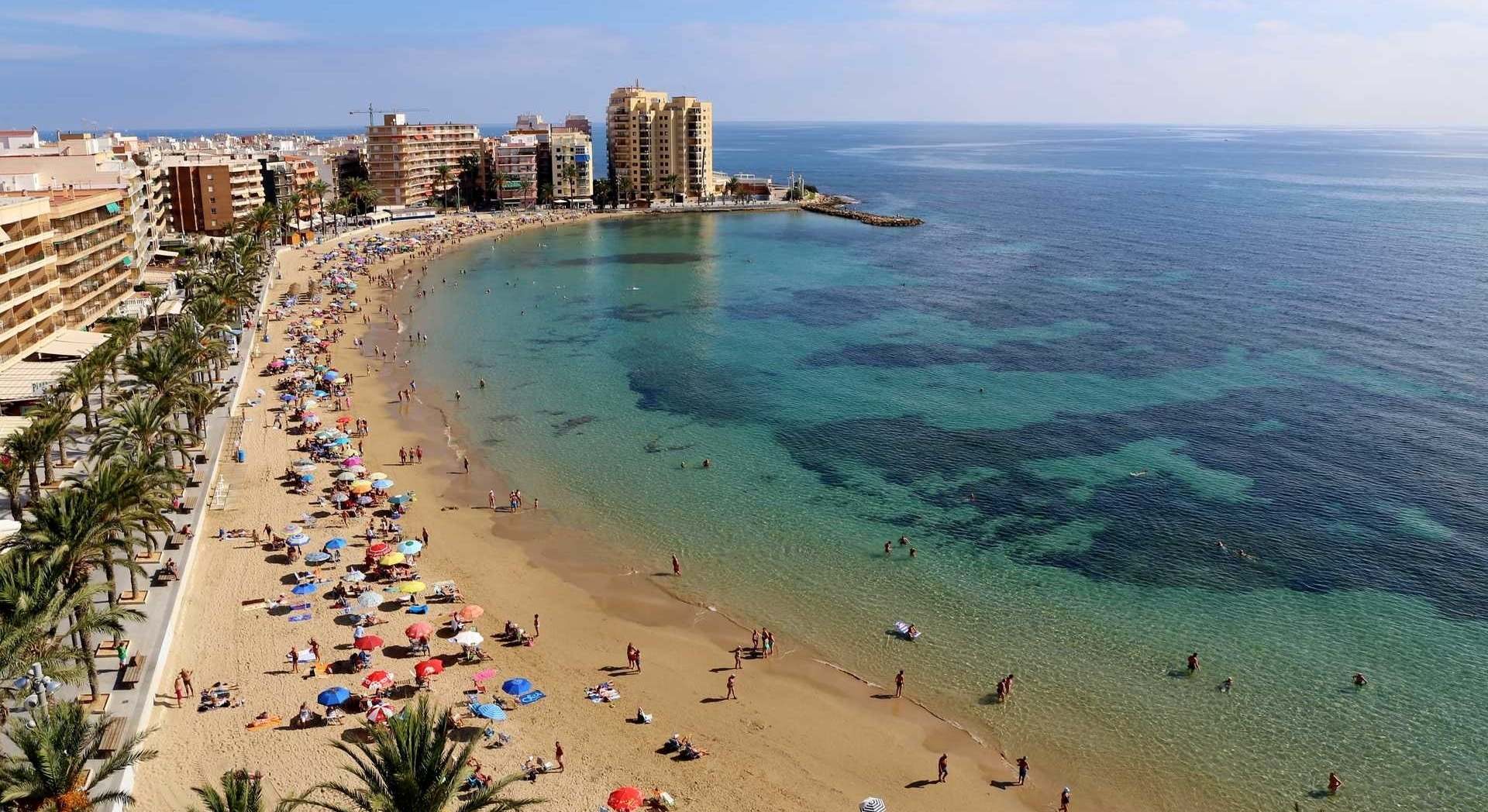 Playa de Alicante muy extensa con gente y edificios.