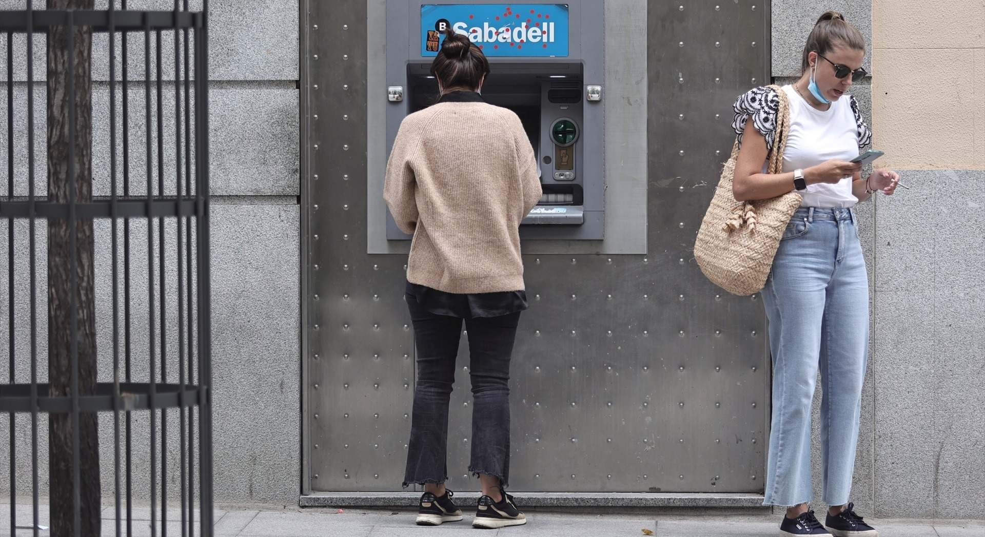 Dos mujeres en un cajero de una sucursal de banco Sabadell | EP