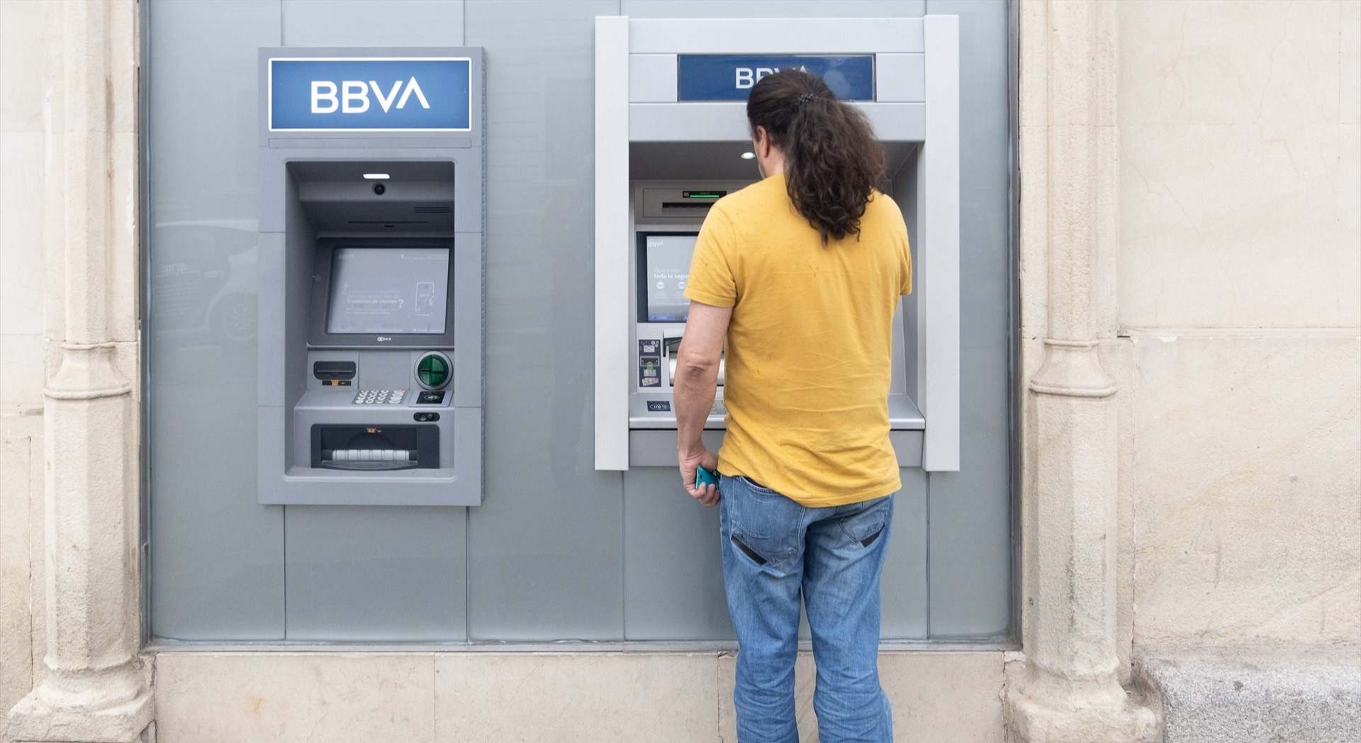 Un hombre saca dinero del cajero.