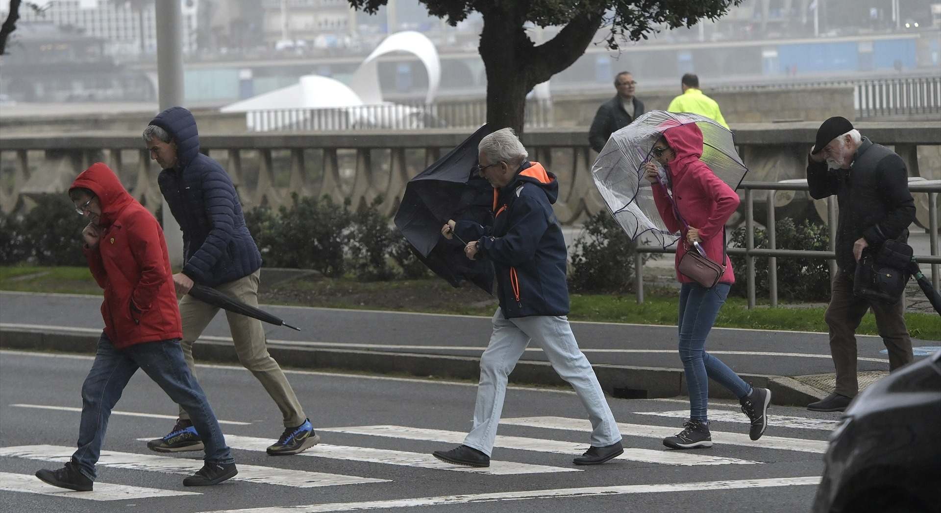 Varias personas se protegen de la lluvia y el viento con paraguas