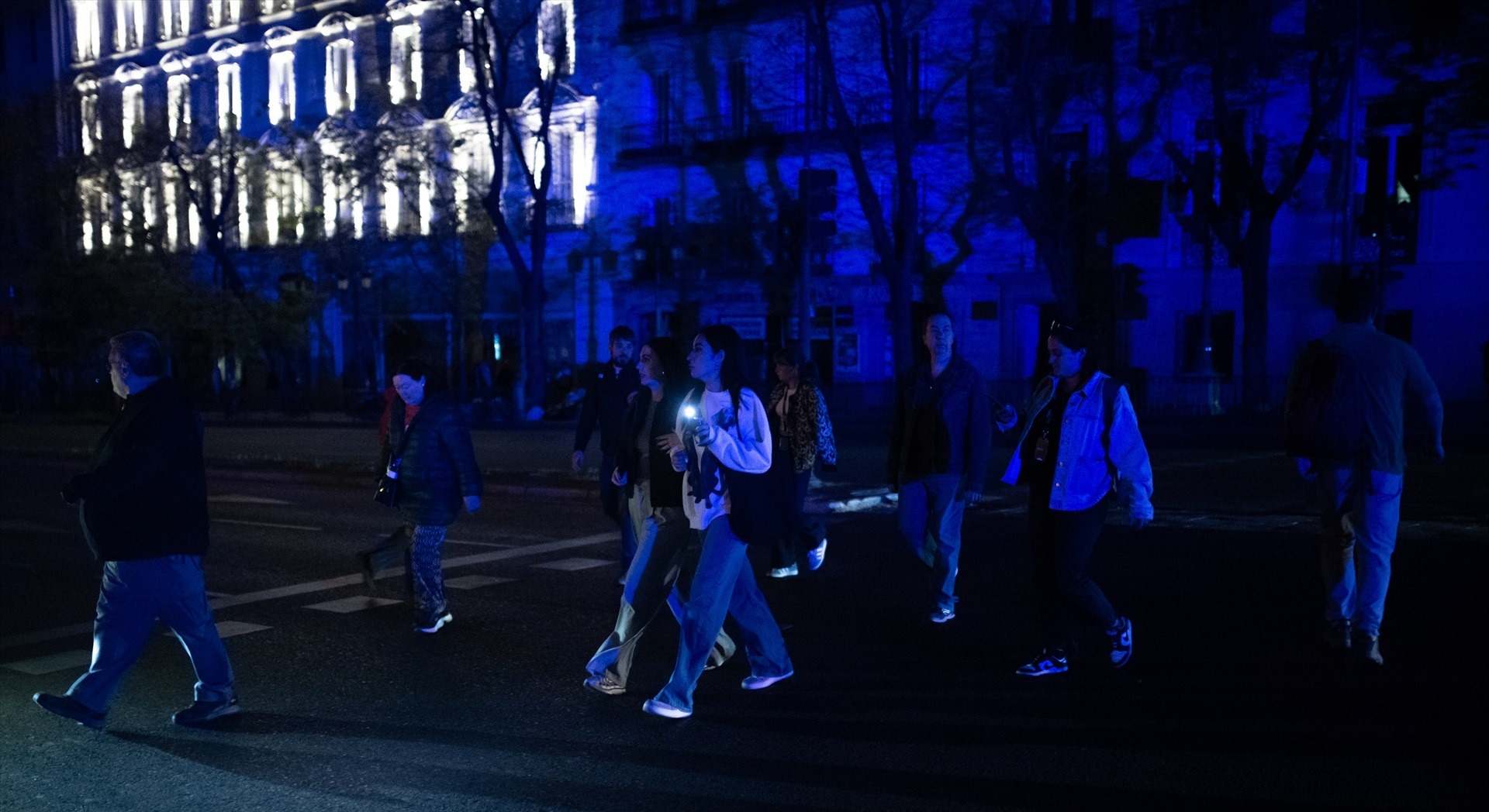 Varias personas cruzan por un paso de peatones tras el apagón eléctrico en Madrid