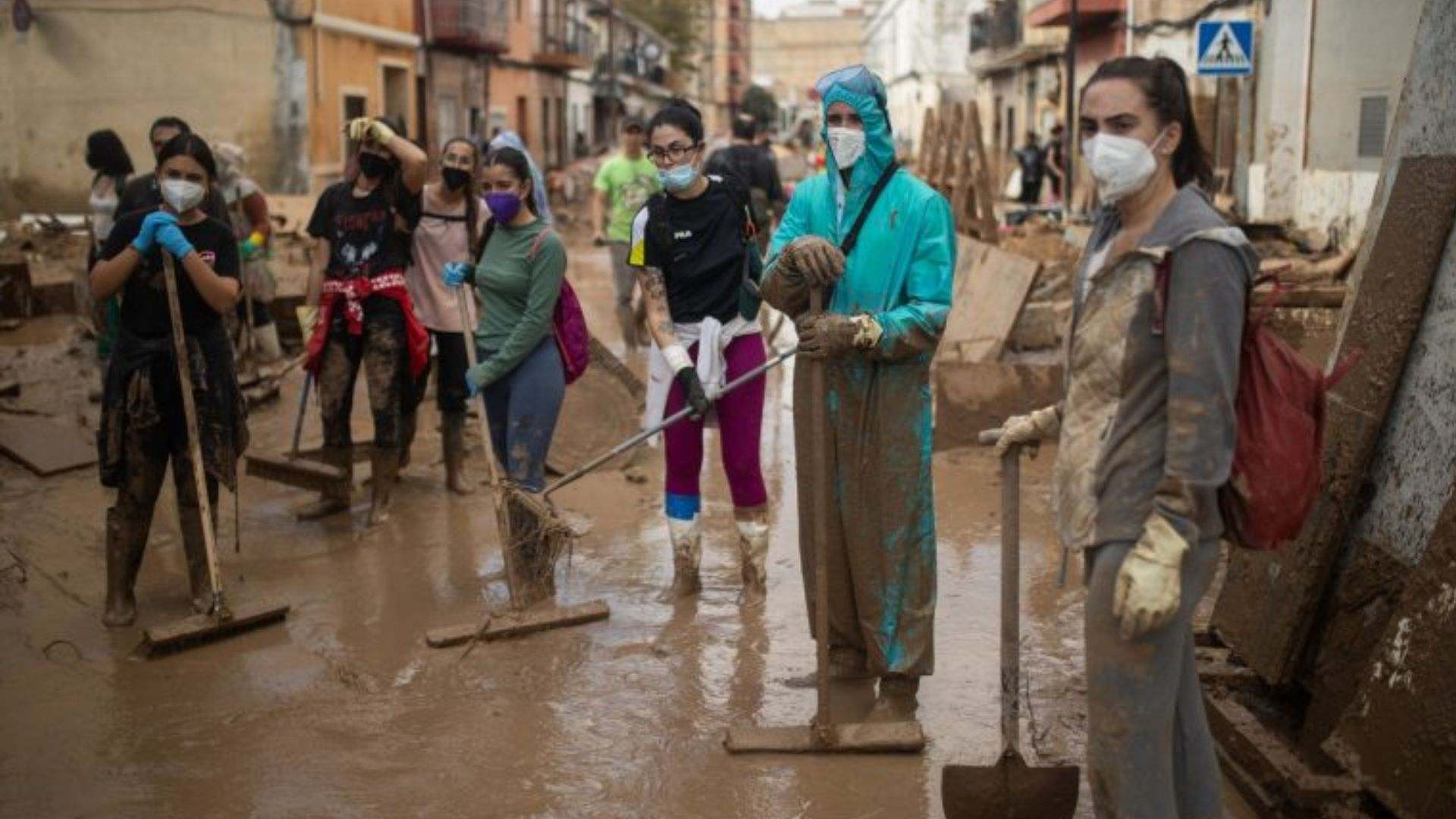 Voluntarios con palas y cepillos retiran barro de las calles del barrio de El Raval.