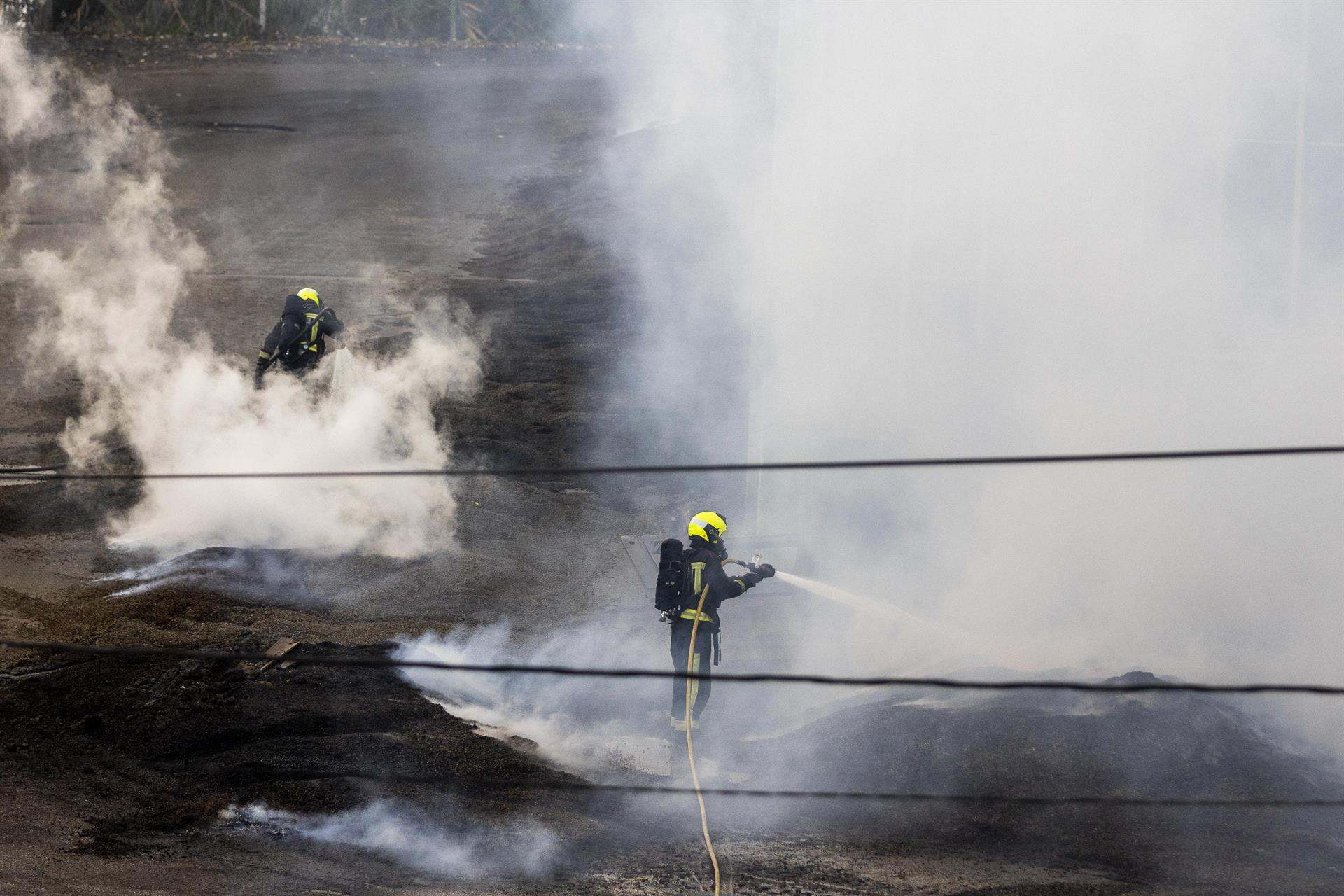 Dos bomberos trabajan en la extinción del fuego de la antigua fábrica de Pontesa, en Ponte Sampaio, (Pontevedra).