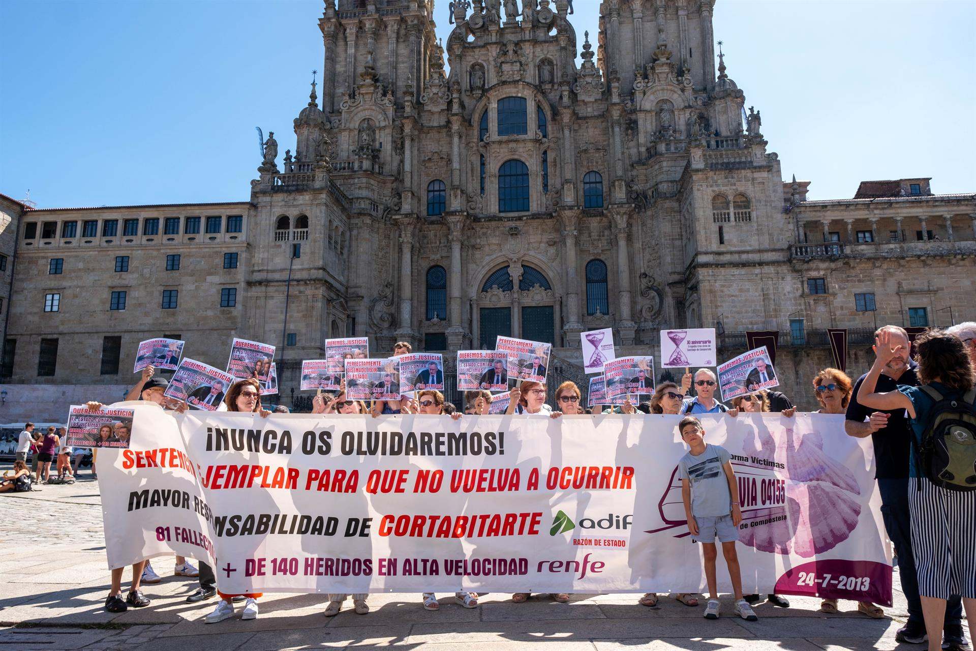 Varias personas con una pancarta durante una concentración de las víctimas de Angrois, frente a la Catedral de Santiago.