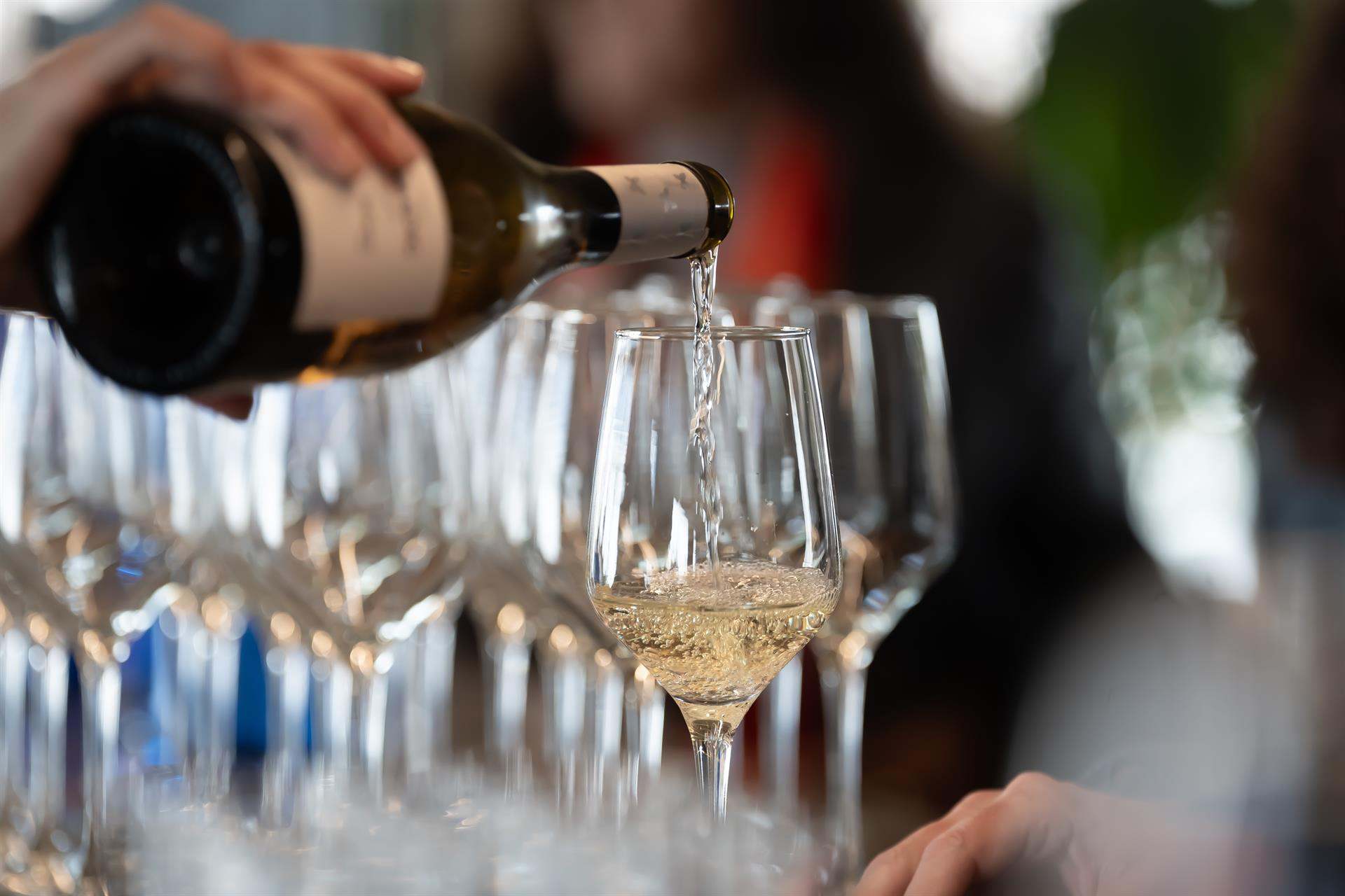 Un camarero sirve una copa de vino blanco
