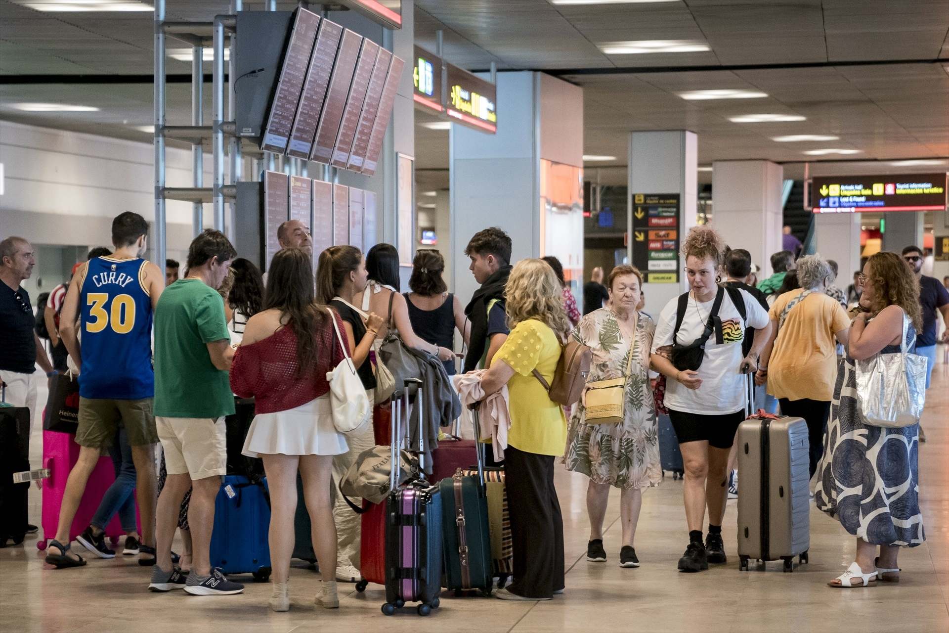 Turistas miran información de vuelos en un aeropuerto.