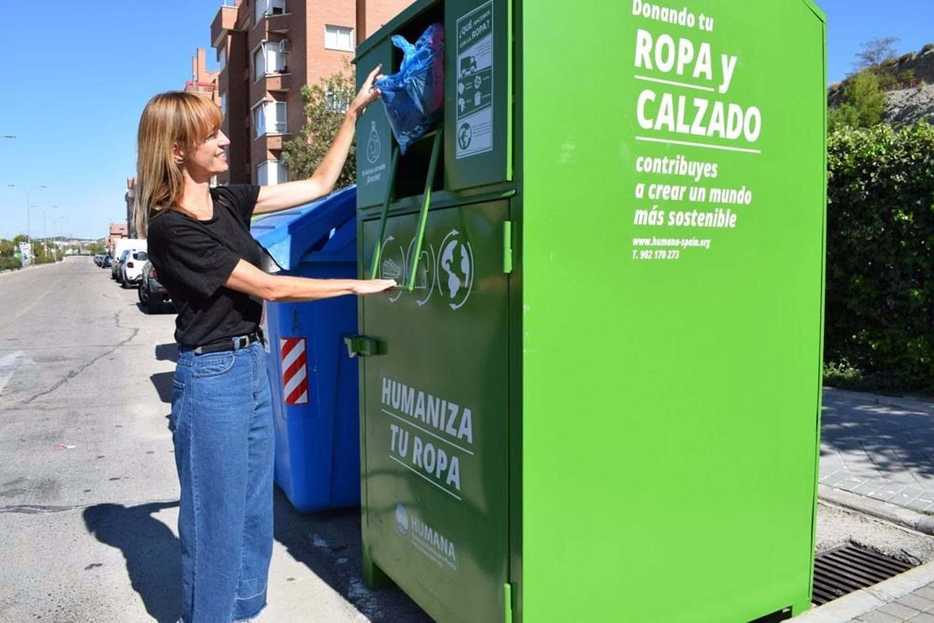 Usuario depositando ropa usada en el contenedor de reciclaje.
