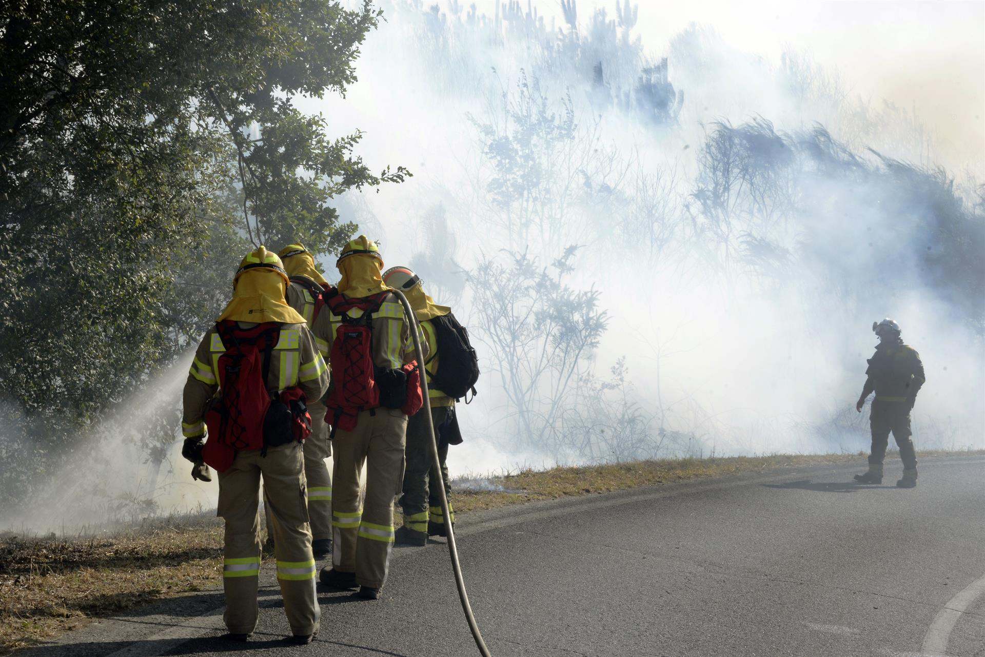Varios bomberos tratan de apagar el fuego durante el incendio forestal en la parroquia de Oseira, en San Cristovo de Cea, Ourense.