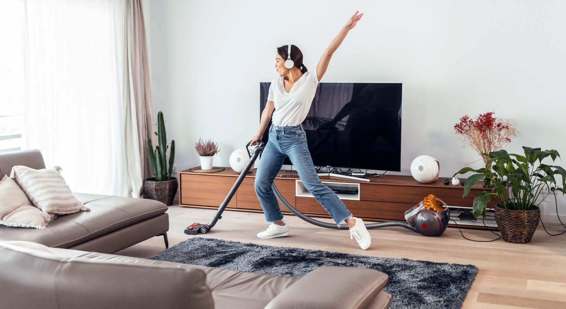 Mujer escuchando y bailando música mientras limpia el piso con un aspirador