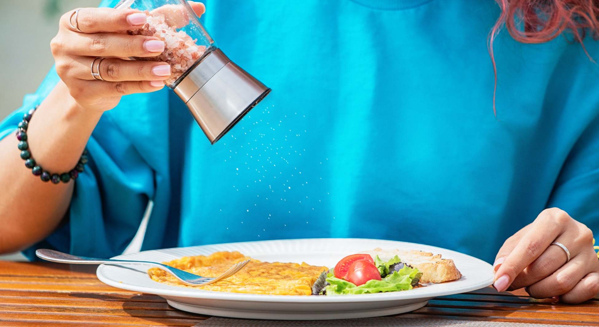 Mujer añadiendo sal a un plato de comida