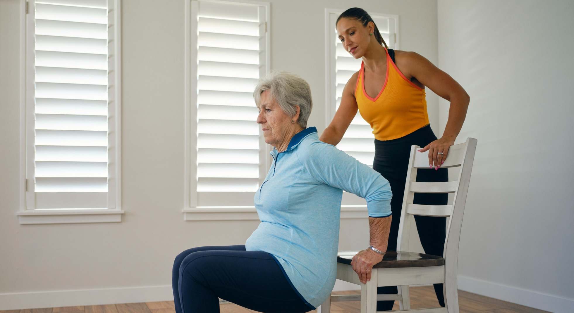 Mujer mayor haciendo ejercicio desde casa con su entrenadora