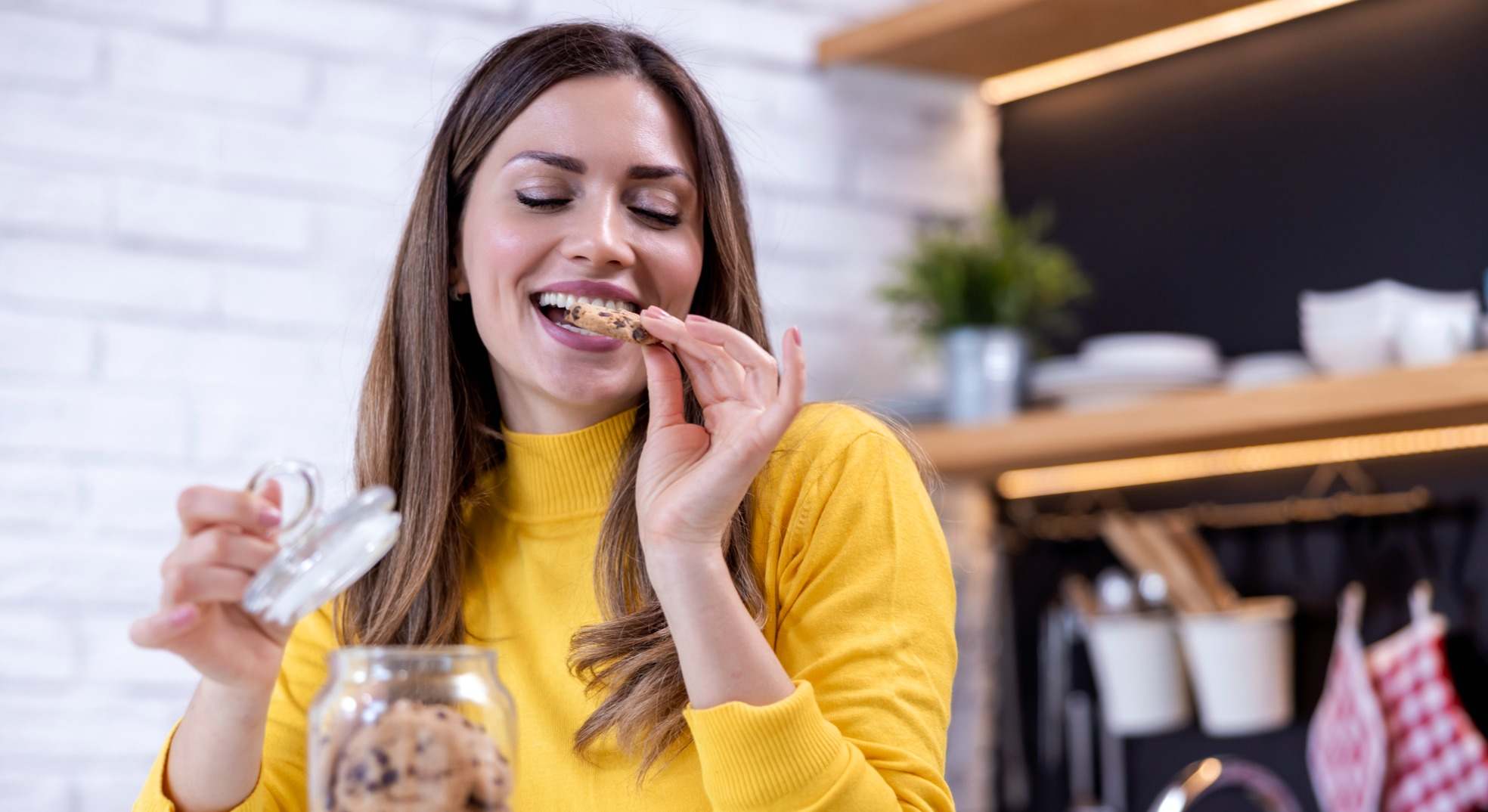 Mujer feliz comiendo galletas de un tarro