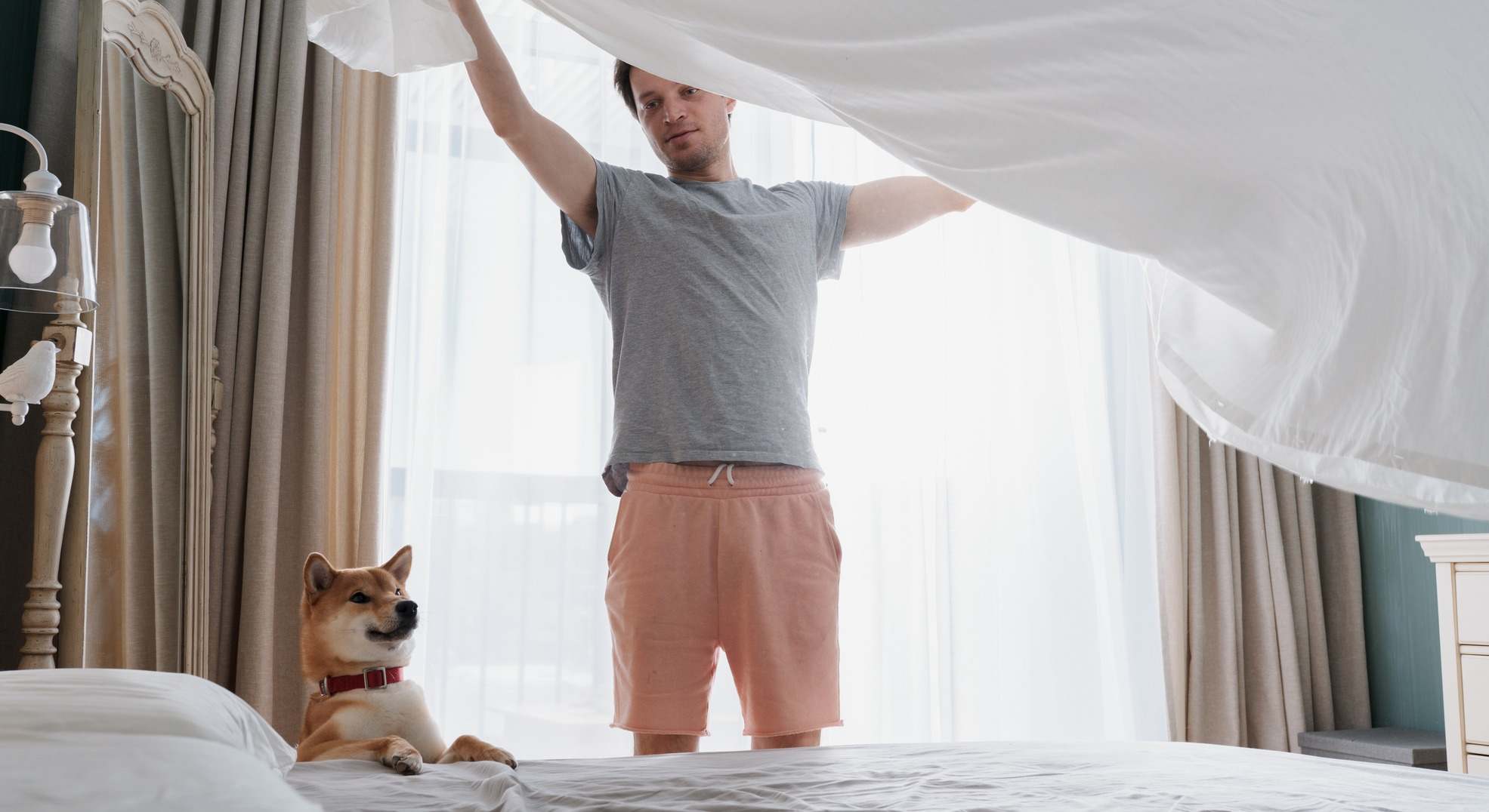 Joven haciendo la cama junto a su perro