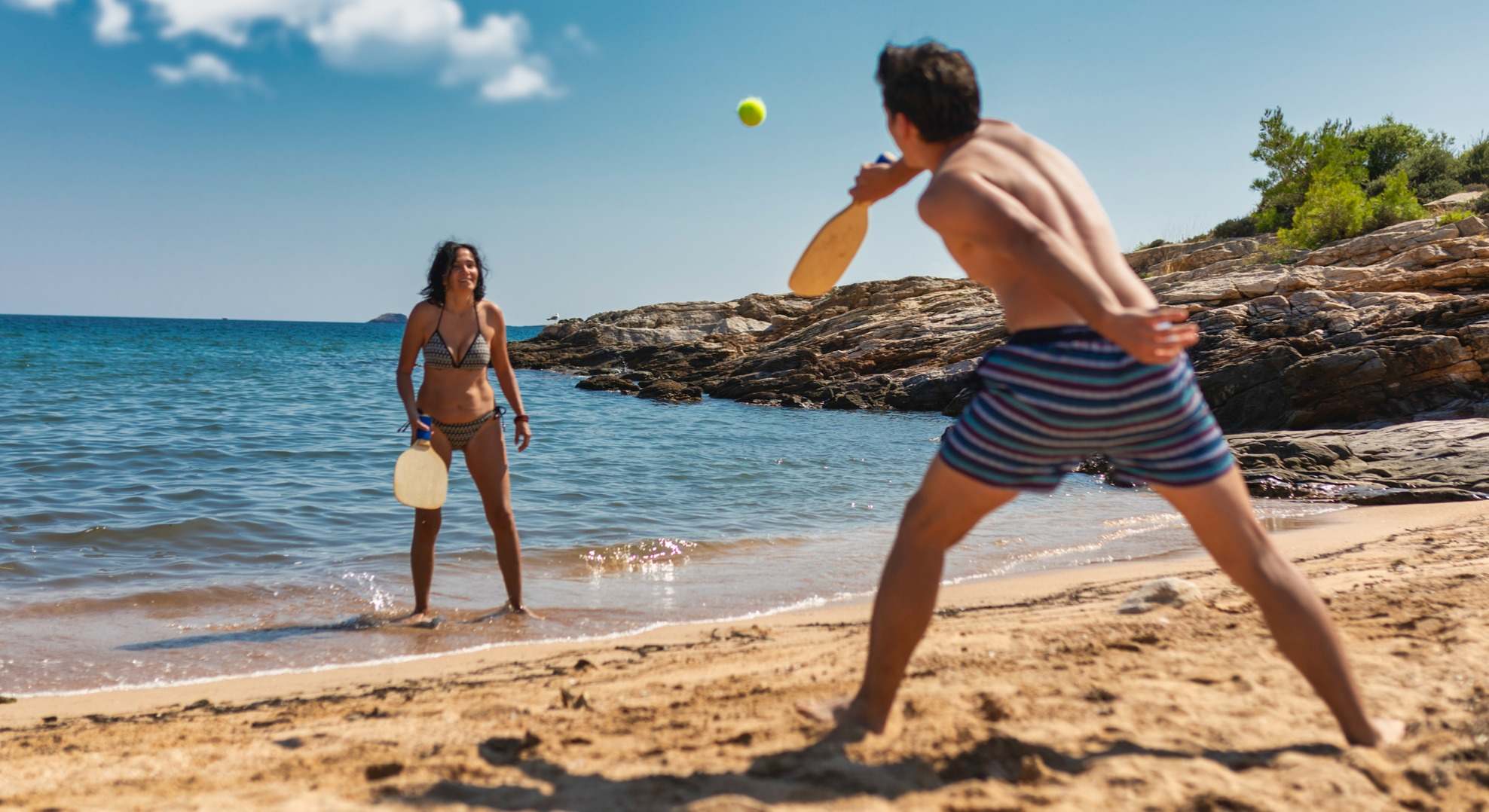 Pareja joven jugando a las palas en la playa