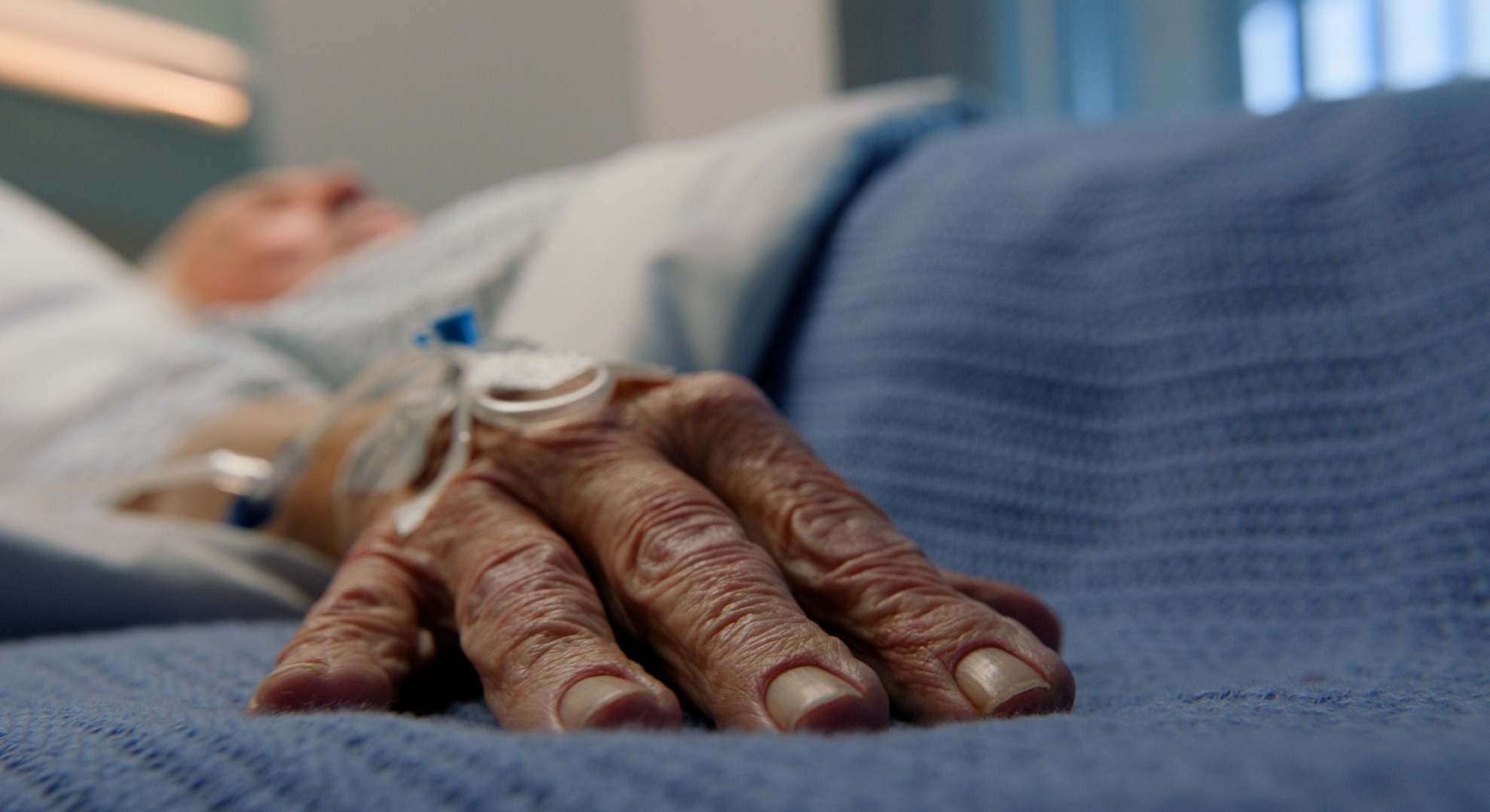 Primer plano de la mano de un hombre en la cama de un hospital