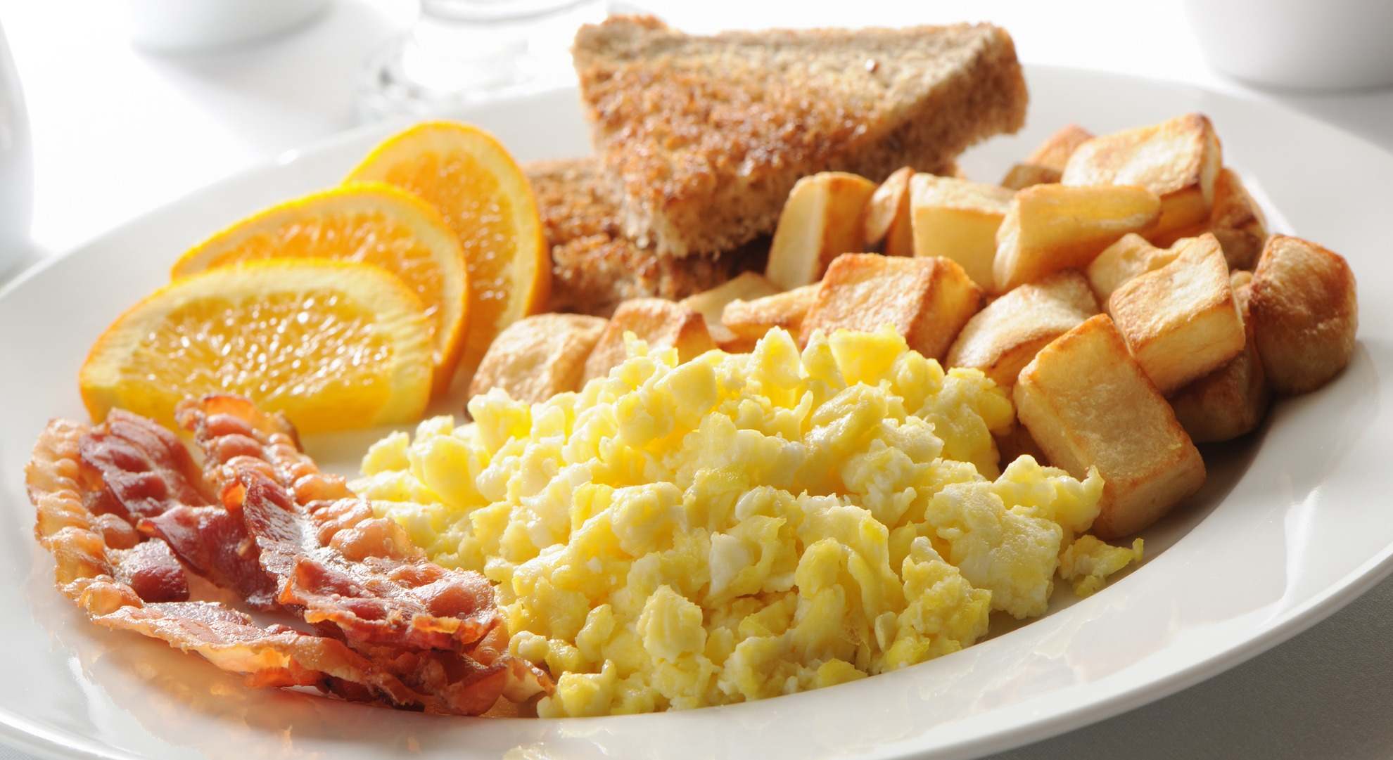 Desayuno completo con patatas, huevo, bacon, naranja y pan
