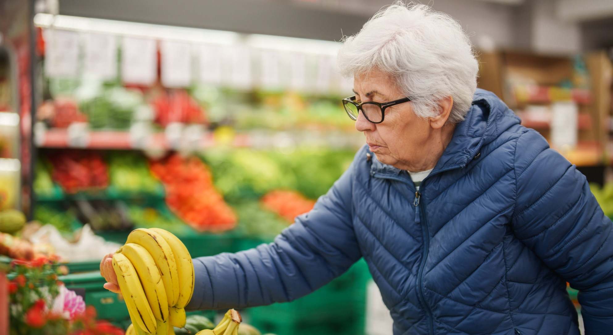 Mujer mayor comprando plátano en el supermercado