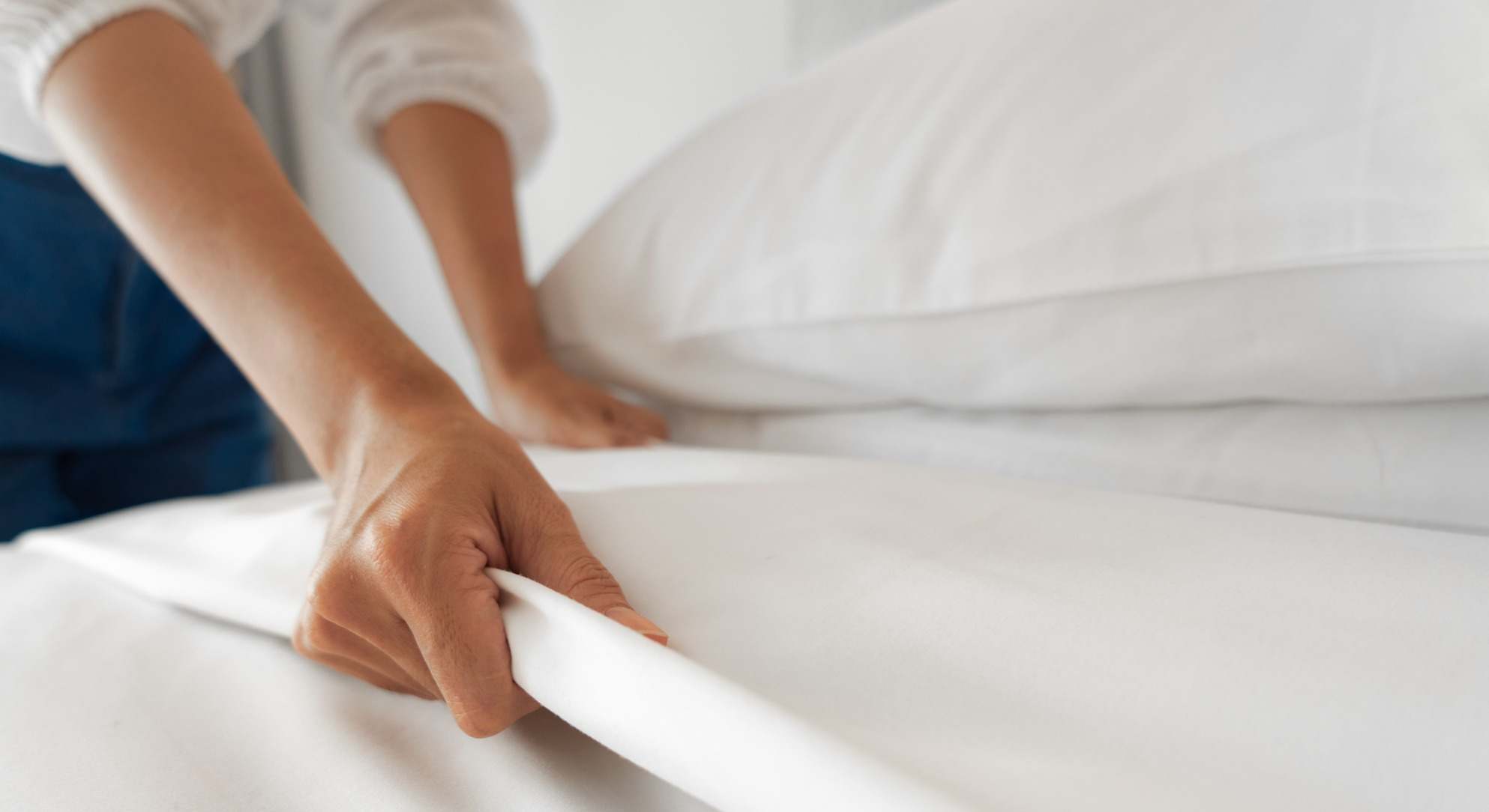 Manos colocando las sábanas en una cama