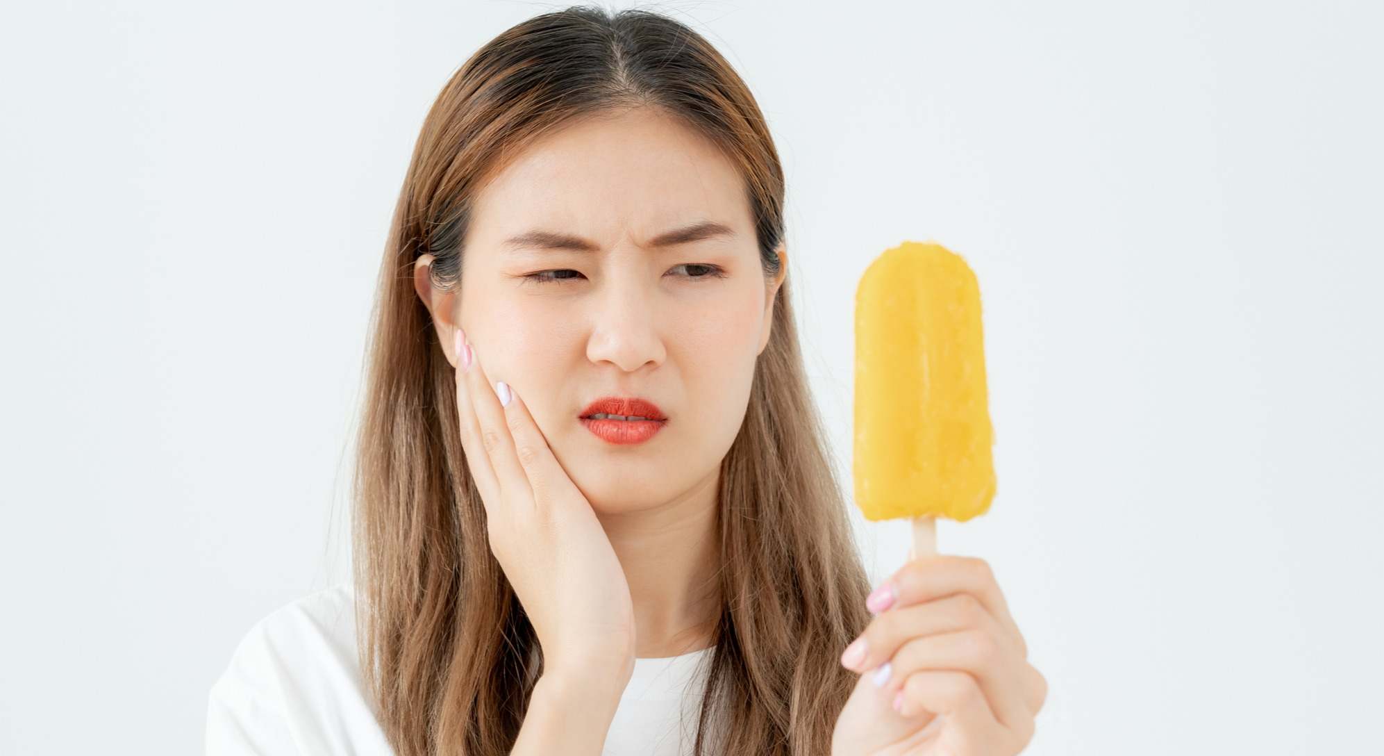 Mujer comiendo helado con sensibilidad dental